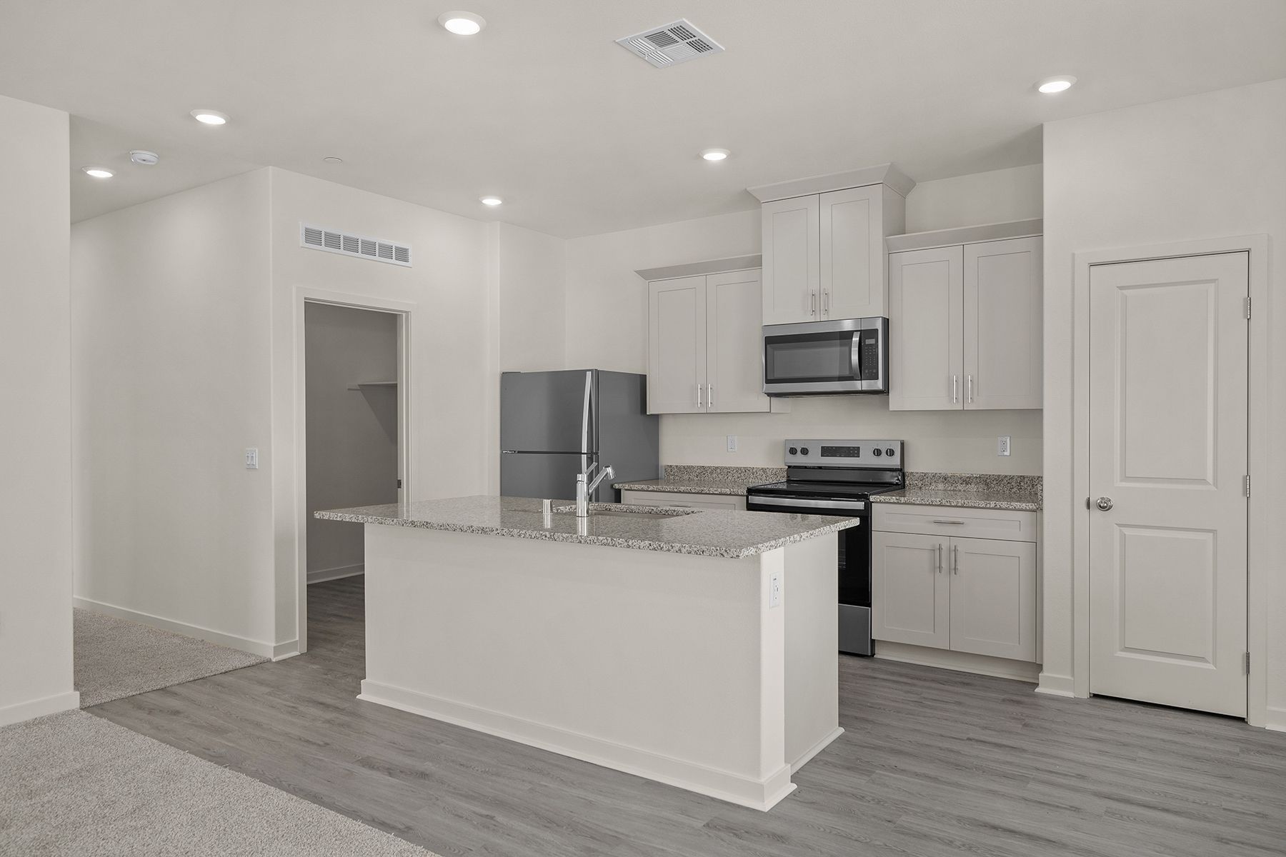 The kitchen has stainless steel appliances and plank flooring.