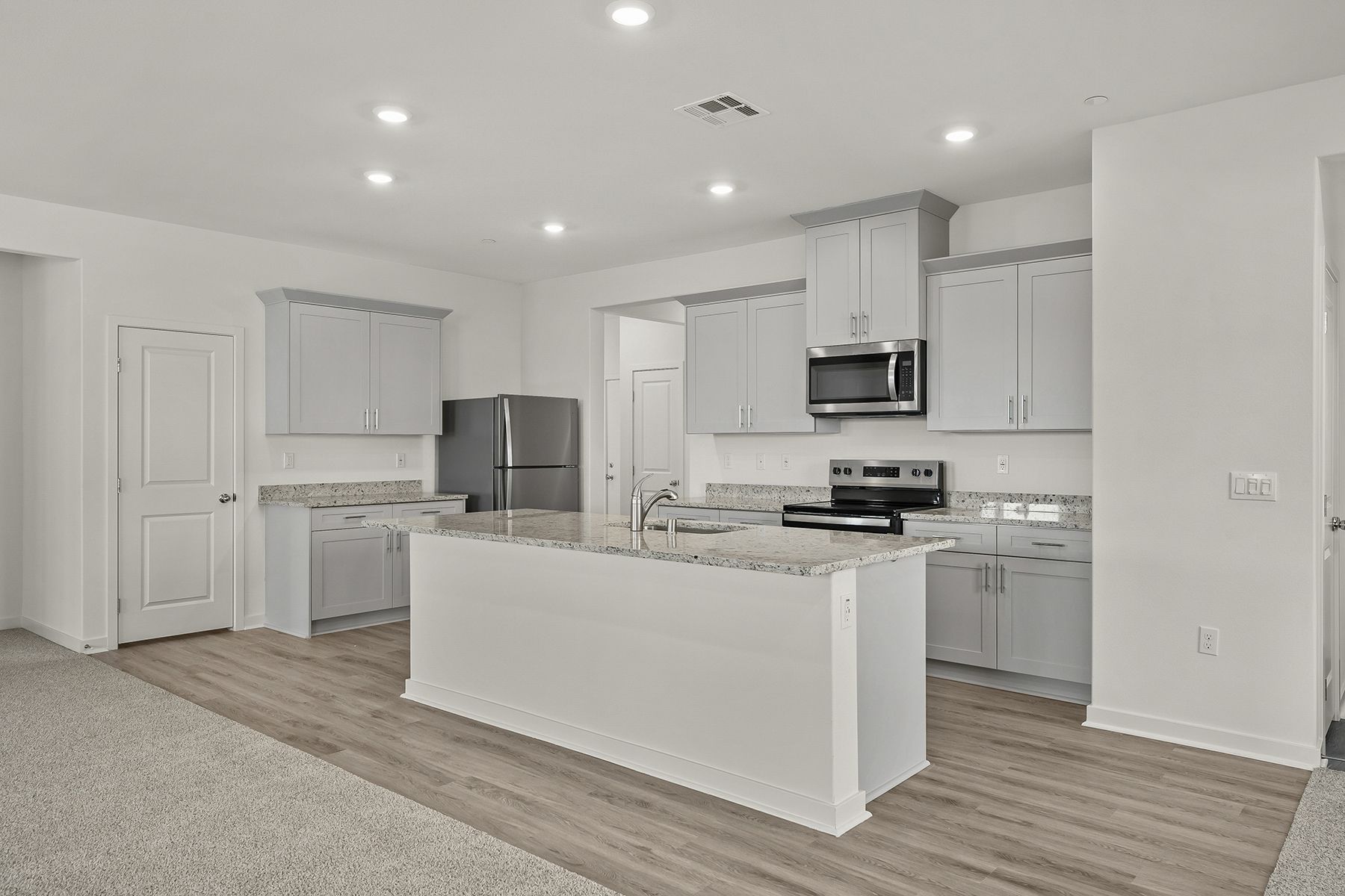 The kitchen has stainless steel appliances and plank flooring.
