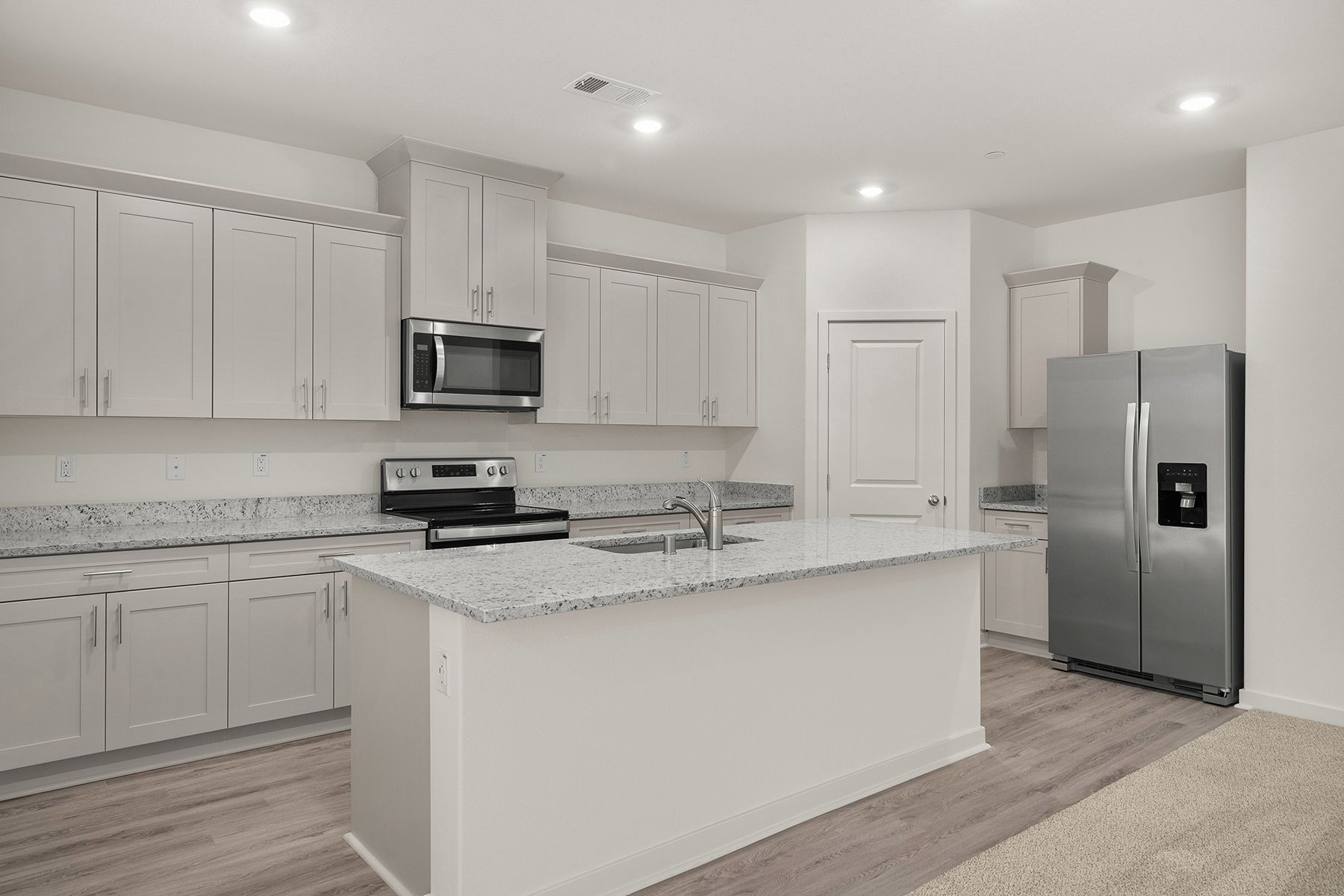 The kitchen has stainless steel appliances and plank flooring.