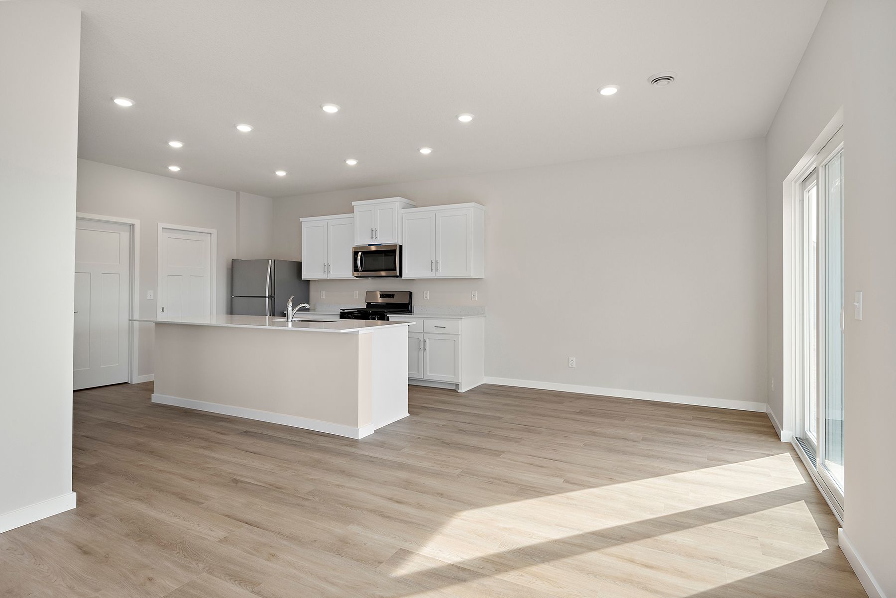 The kitchen has stainless steel appliances and plank flooring.
