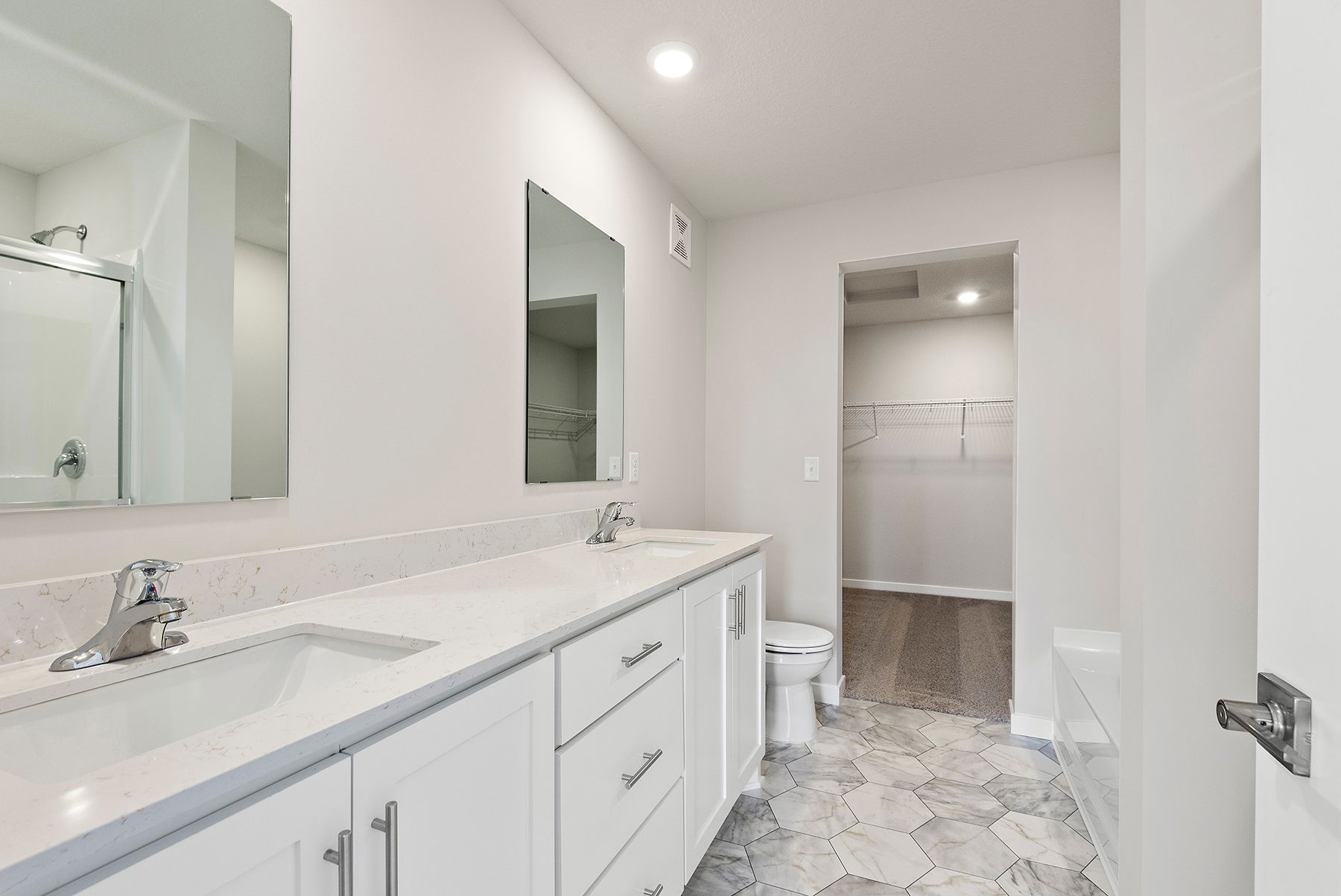 The master bathroom has a dual sink vanity and a step in shower and soaking tub
