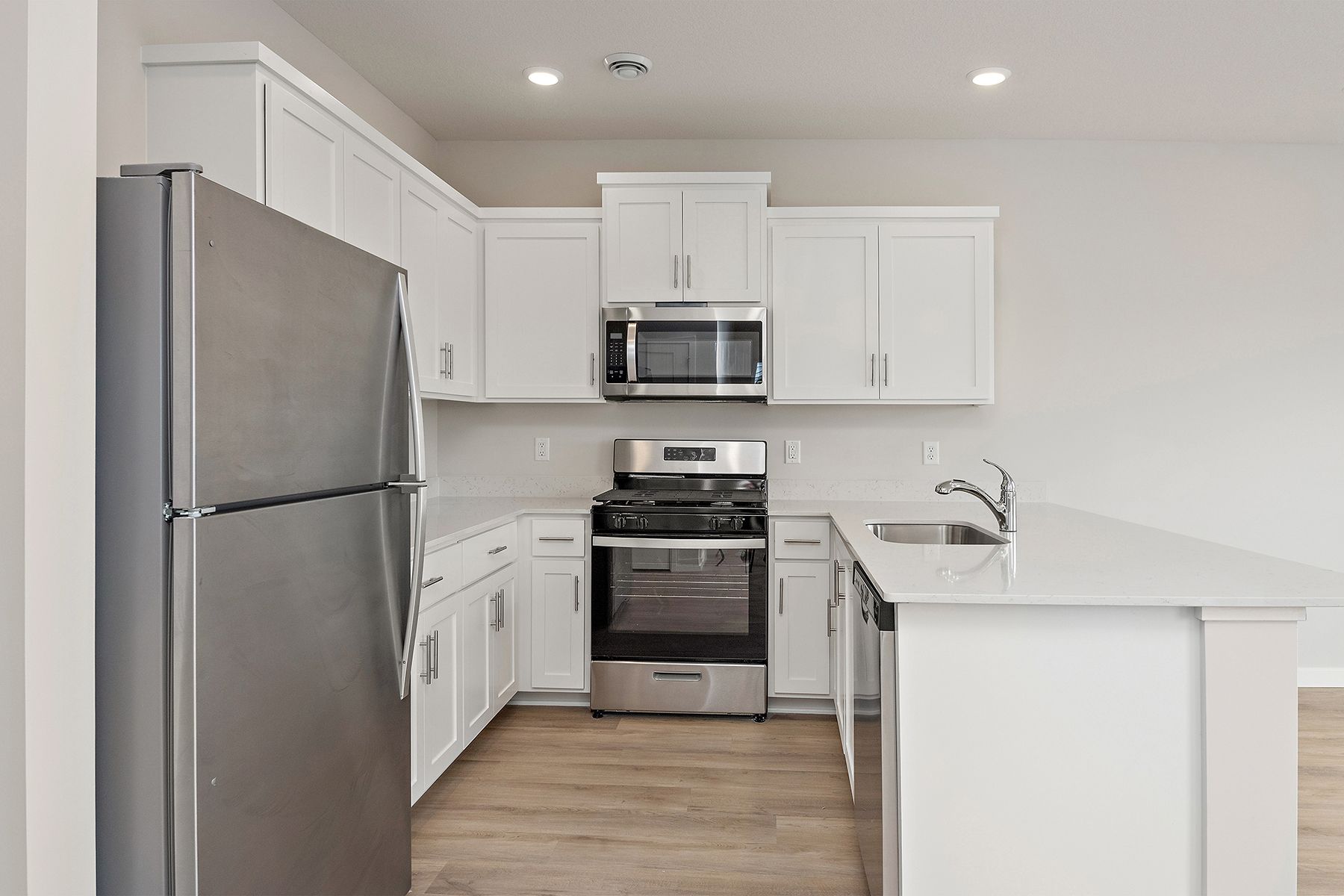 The kitchen has stainless steel appliances and plank flooring.