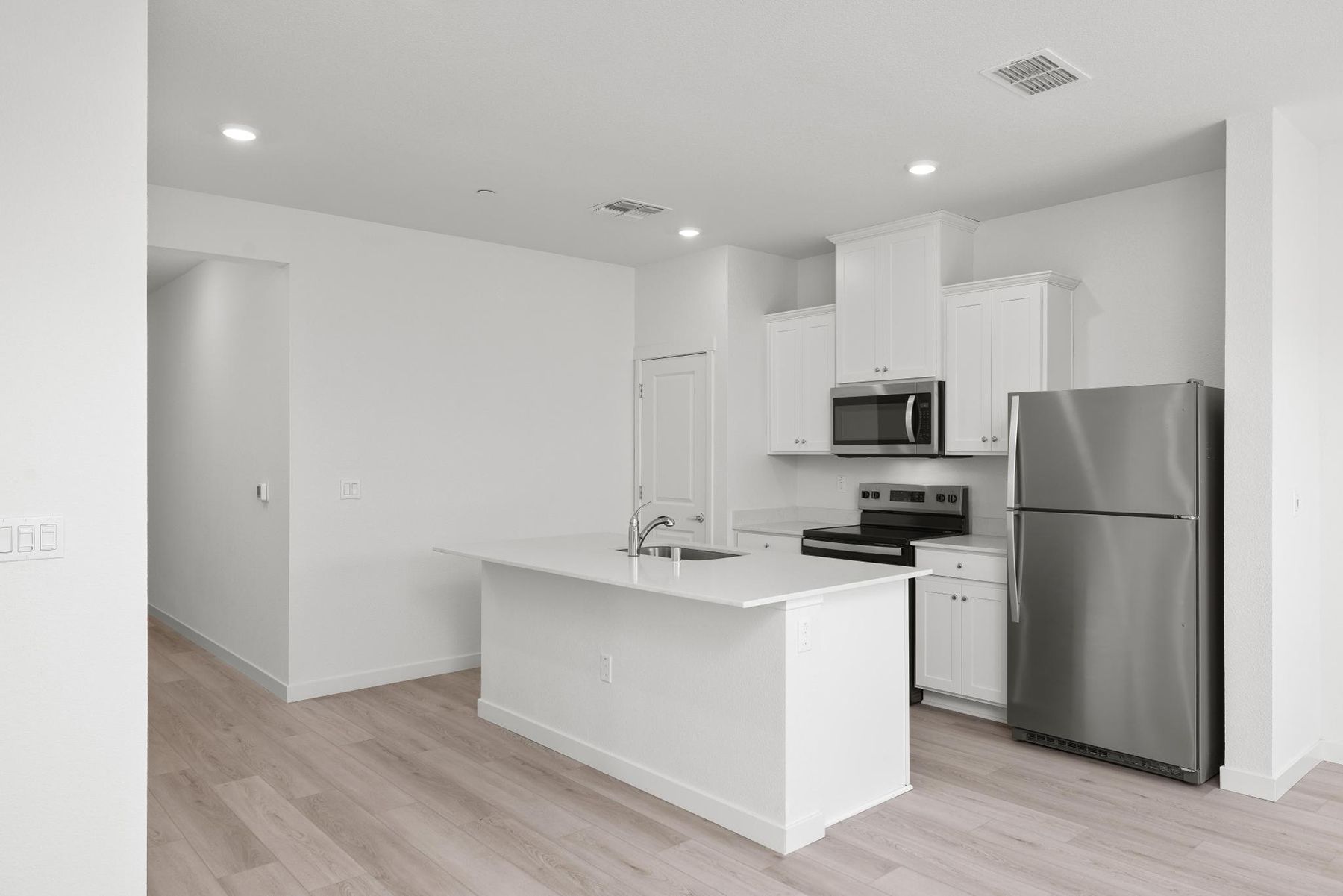 The kitchen has stainless steel appliances and plank flooring.