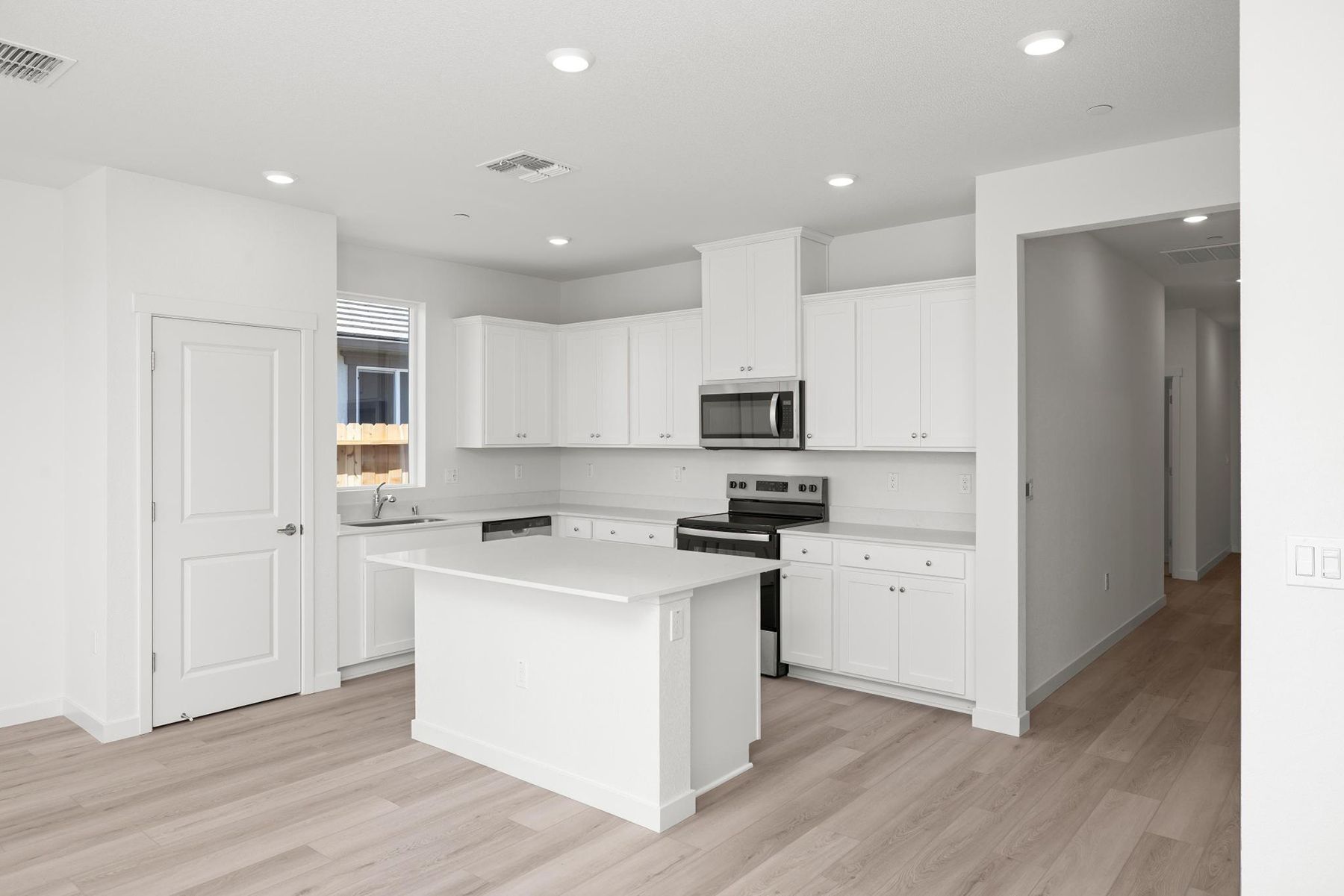 The kitchen has stainless steel appliances and plank flooring.