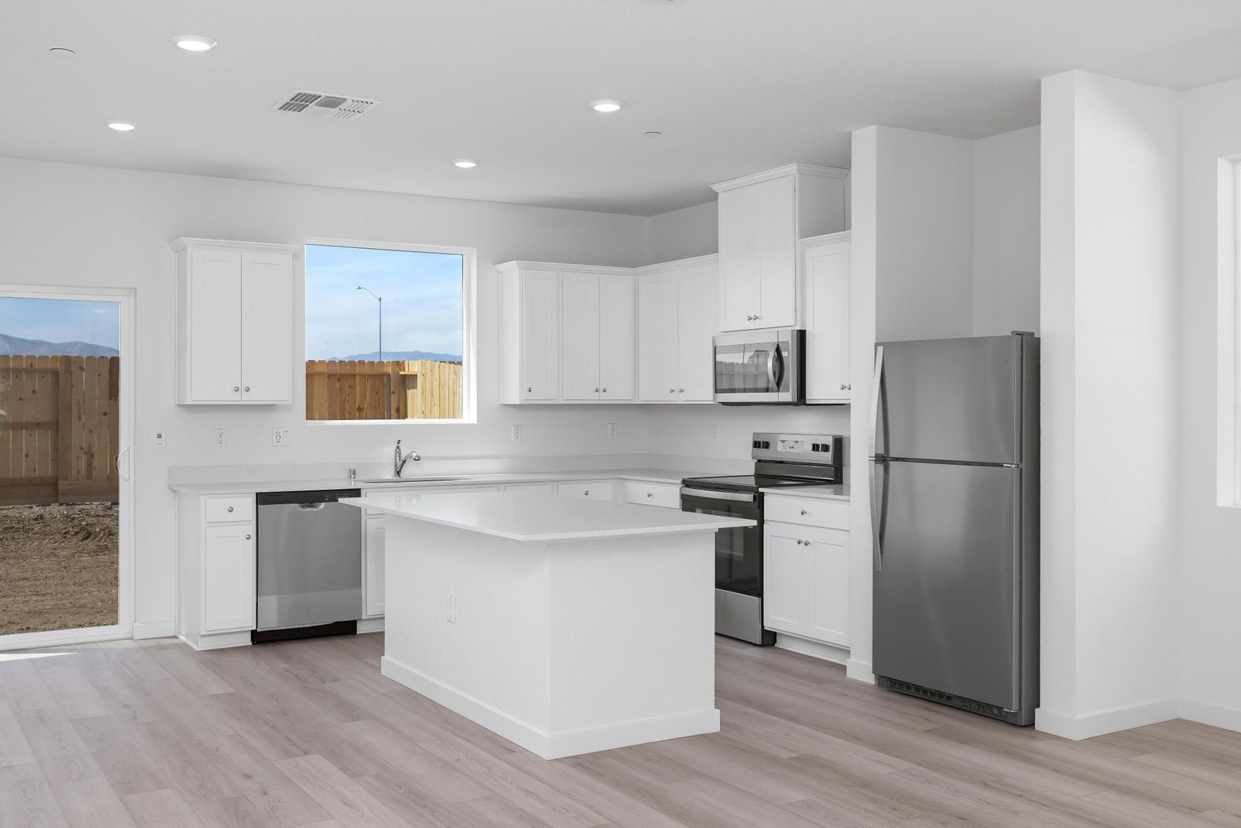 The kitchen has stainless steel appliances and plank flooring.