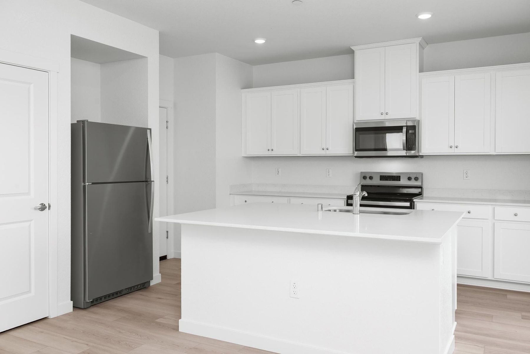 The kitchen has stainless steel appliances and plank flooring.