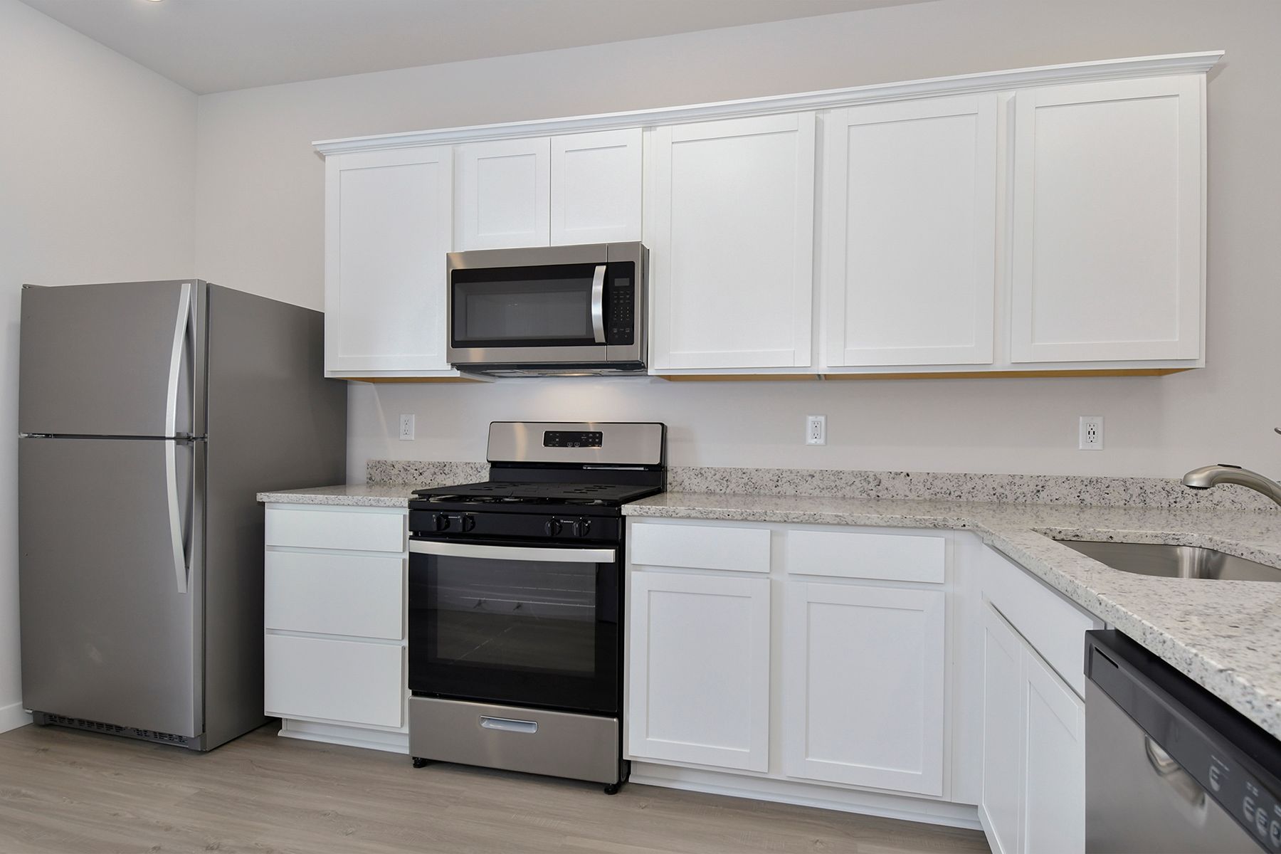 The kitchen has stainless steel appliances and plank flooring.