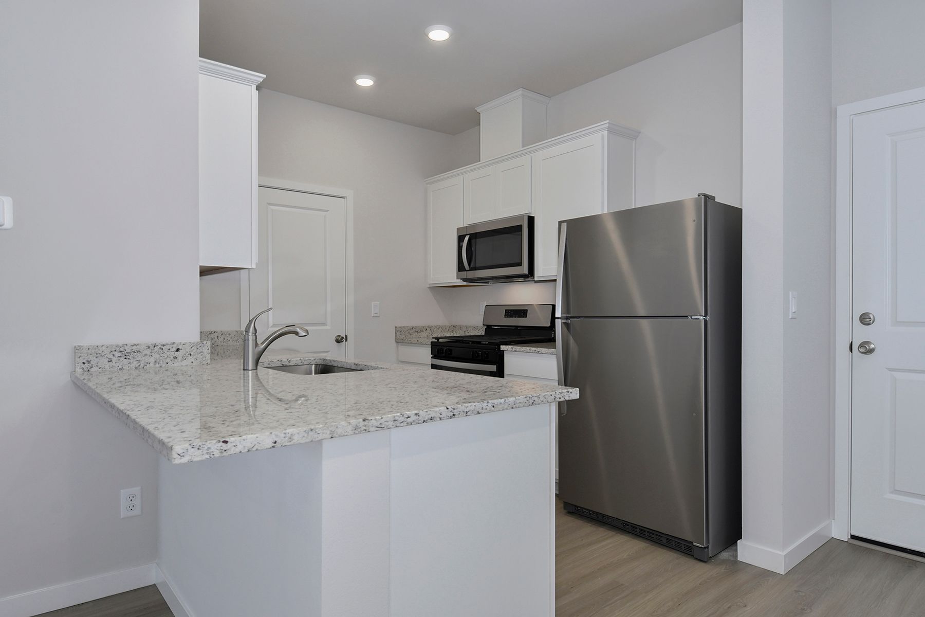 The kitchen has stainless steel appliances and plank flooring.
