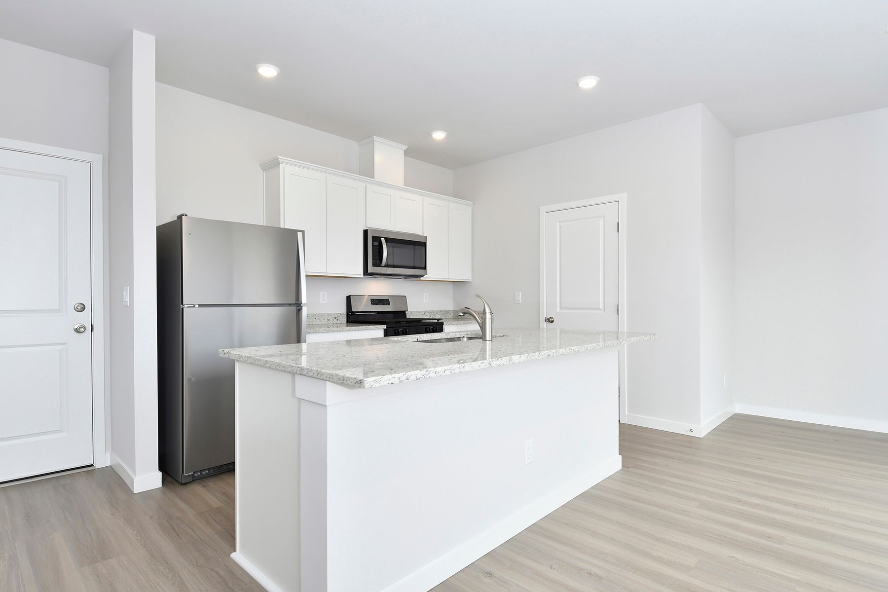 The kitchen has stainless steel appliances and plank flooring.