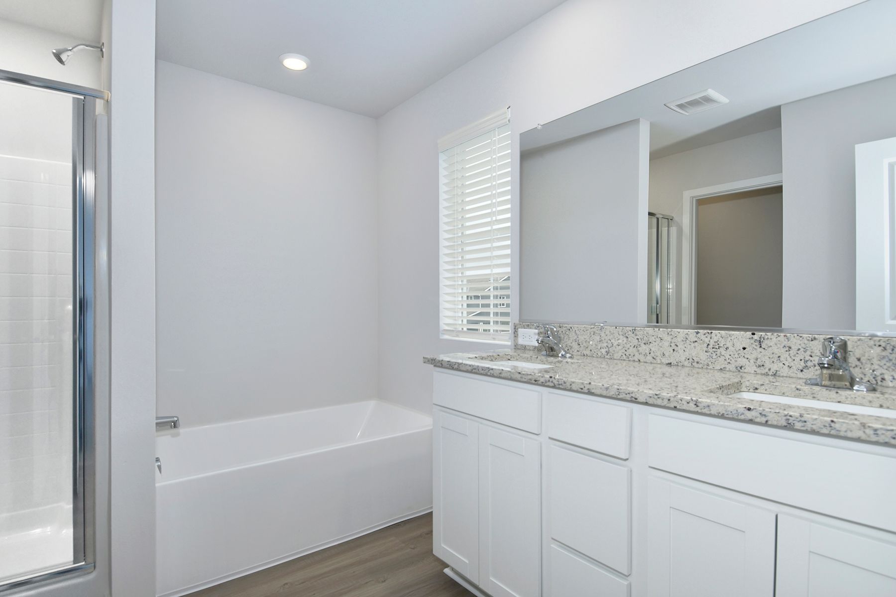 The master bathroom has a dual sink vanity and a step in shower and soaking tub.