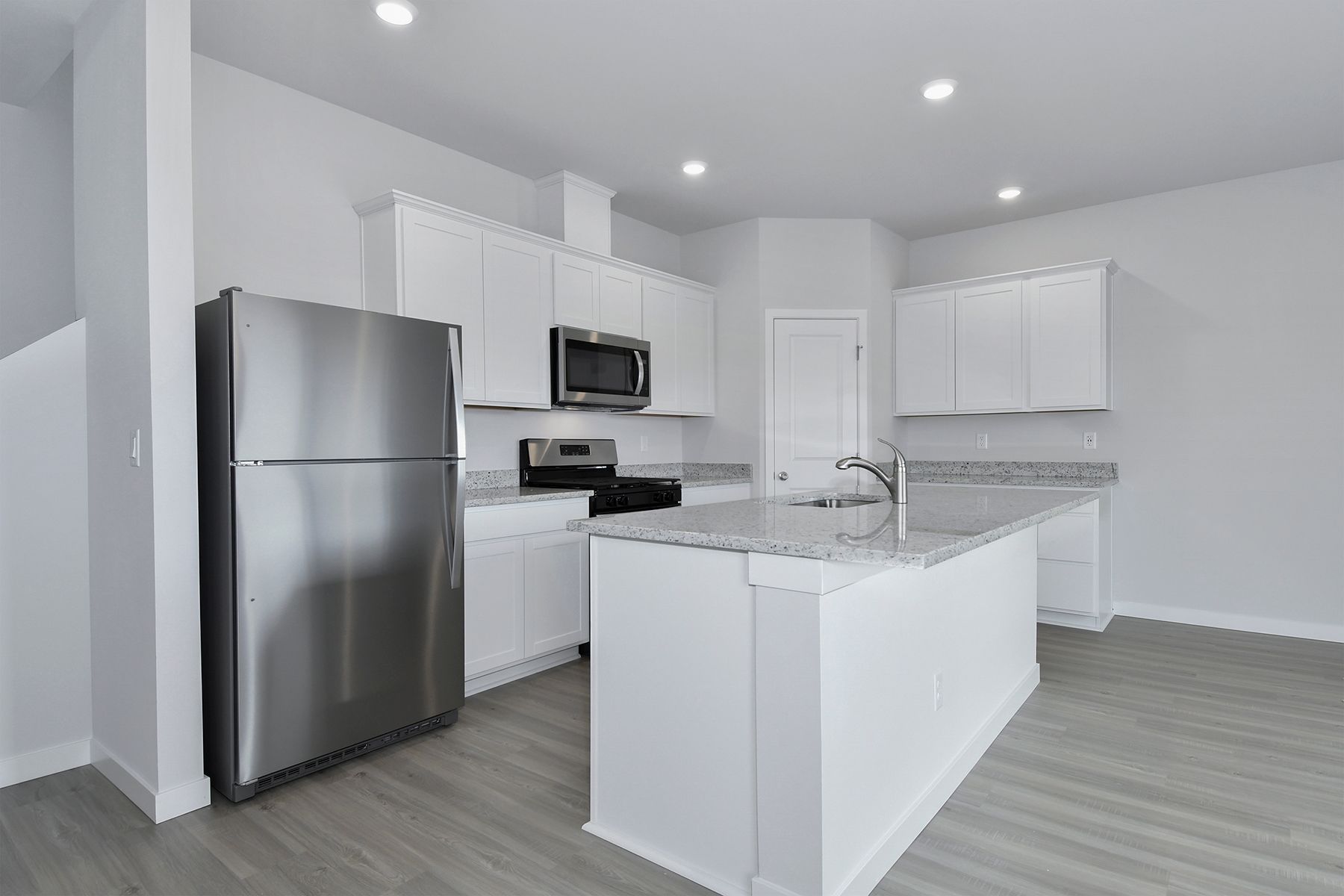 The kitchen has stainless steel appliances and plank flooring.