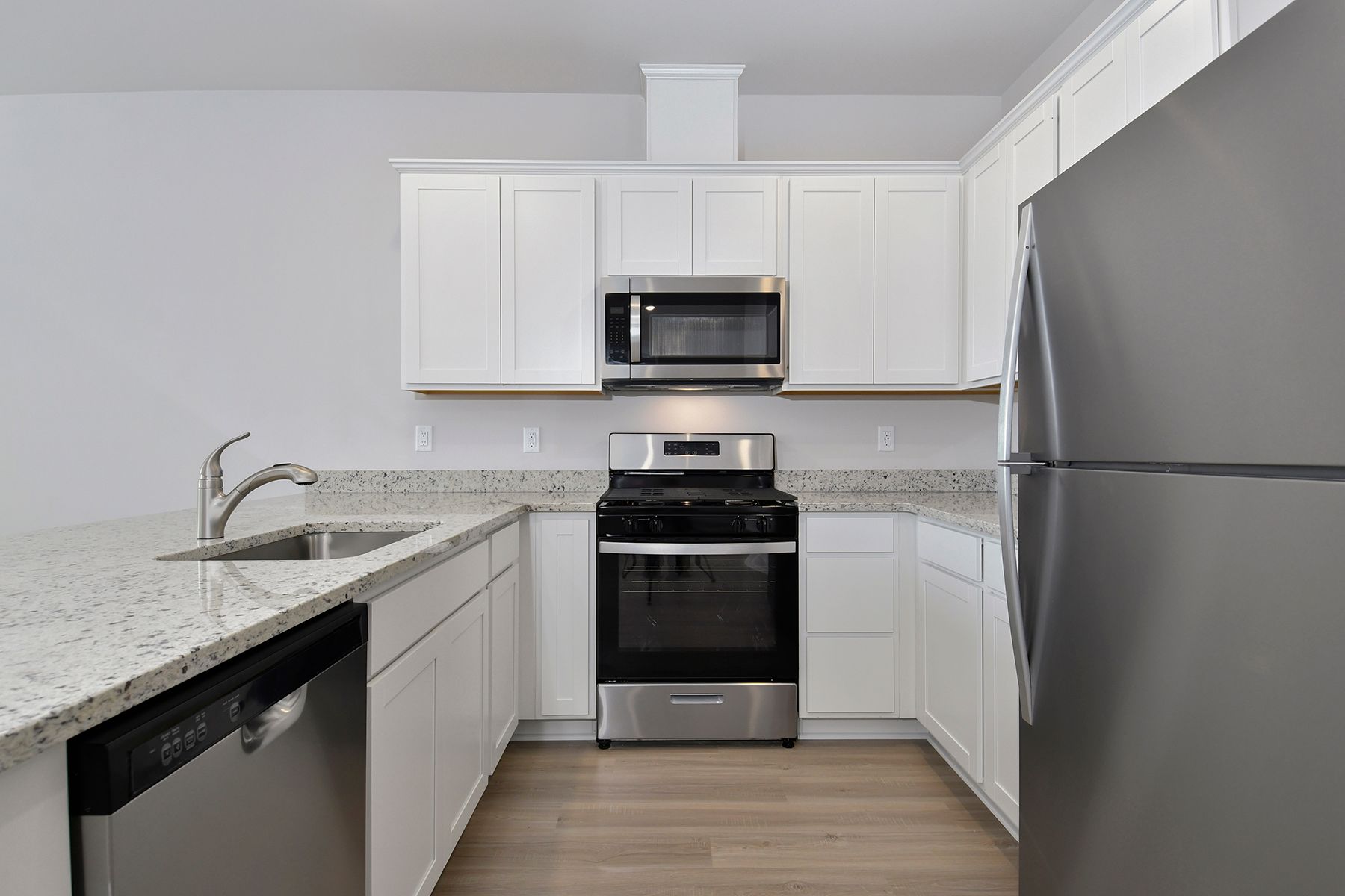 The kitchen has stainless steel appliances and plank flooring.