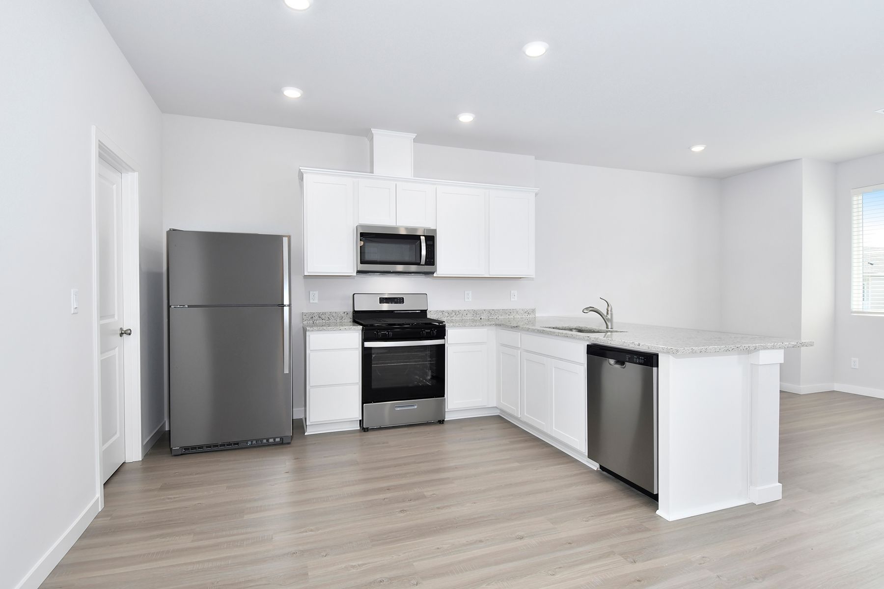 The kitchen has stainless steel appliances and plank flooring.
