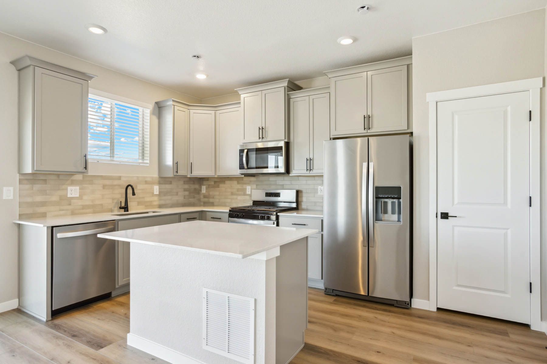 The kitchen has stainless steel appliances and plank flooring.
