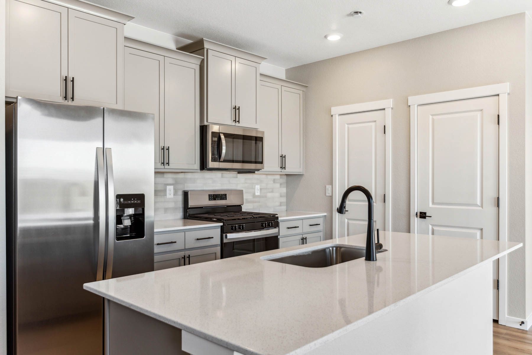 The kitchen has stainless steel appliances and plank flooring.
