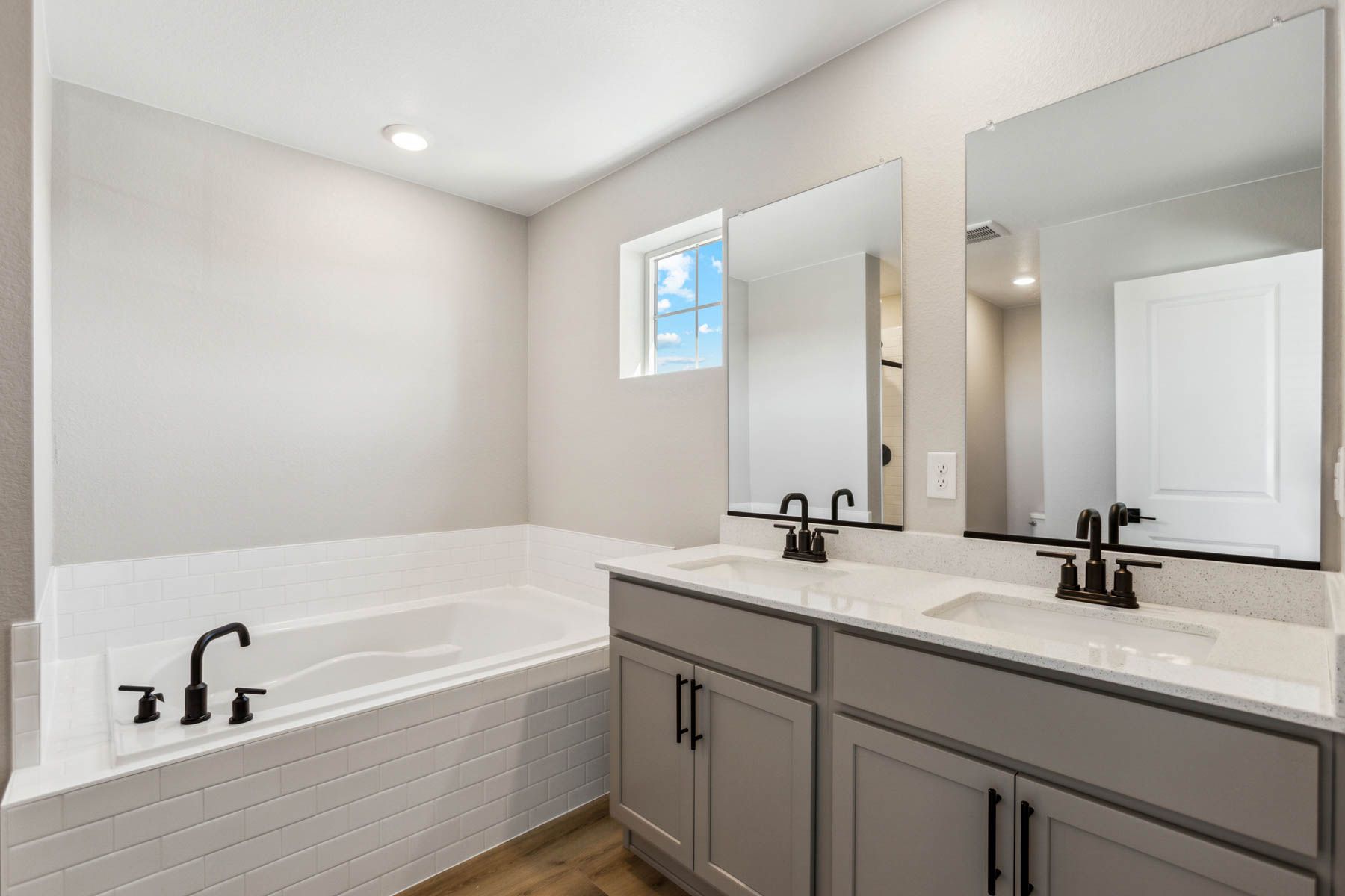 The master bathroom has a dual sink vanity and step in shower and a soaking tub.