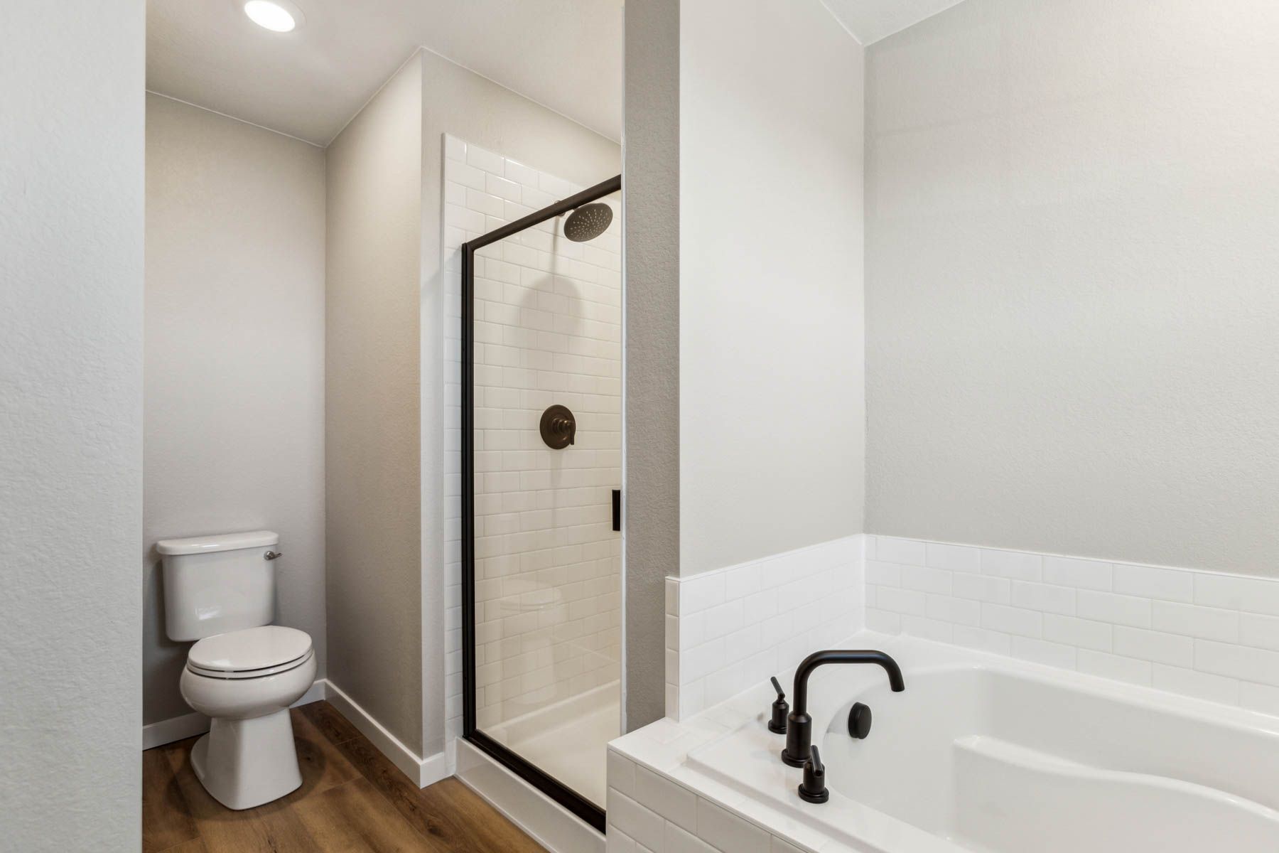 The master bathroom has a dual sink vanity and step in shower and a soaking tub.