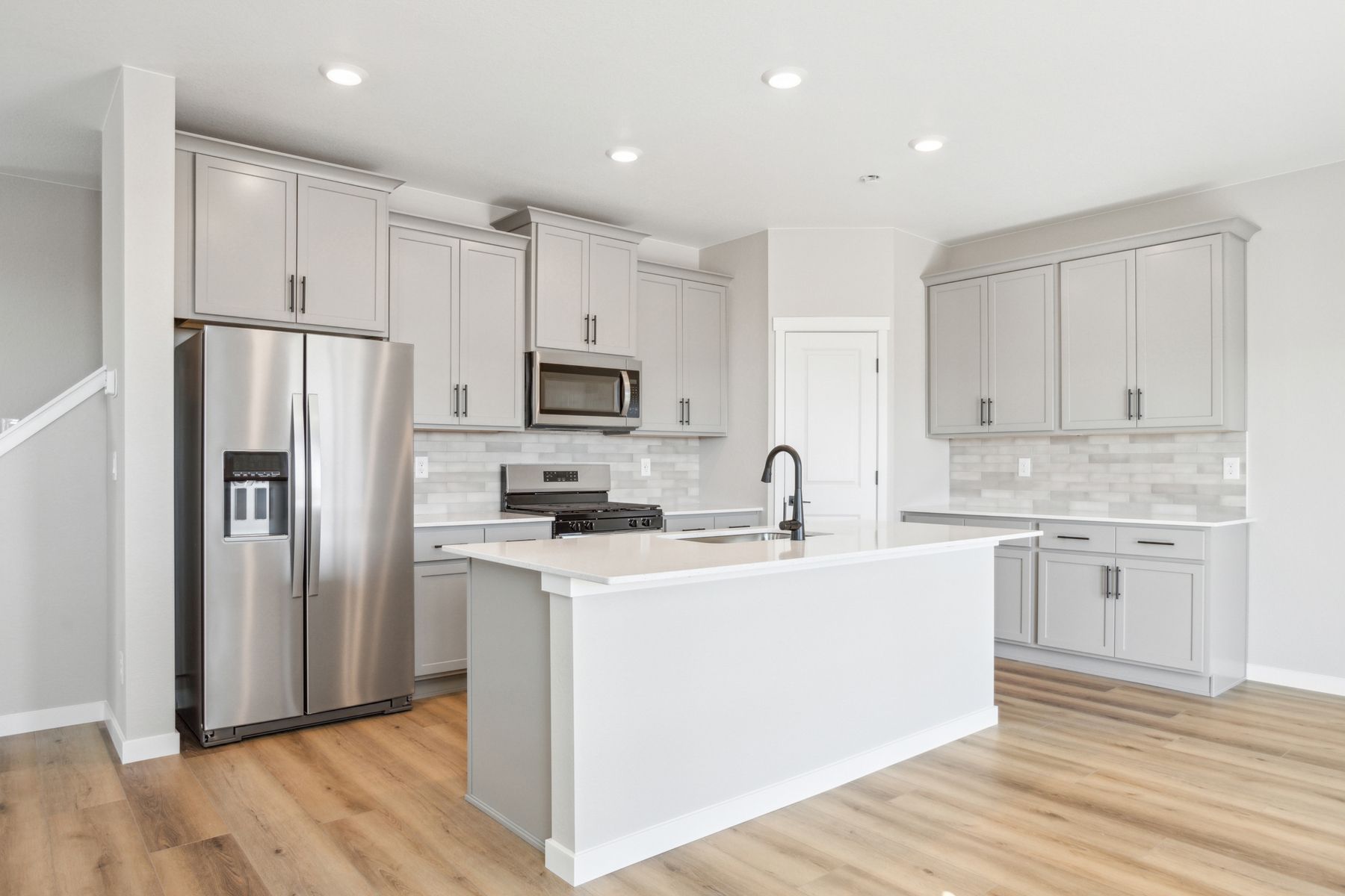 The kitchen has stainless steel appliances and plank flooring.