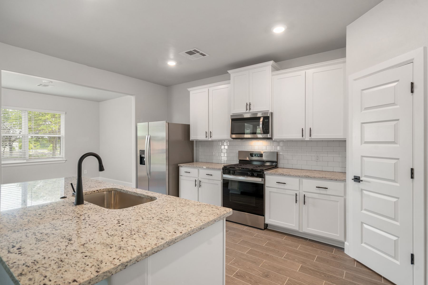 The beautiful kitchen has white wood cabinetry and tile backsplash.