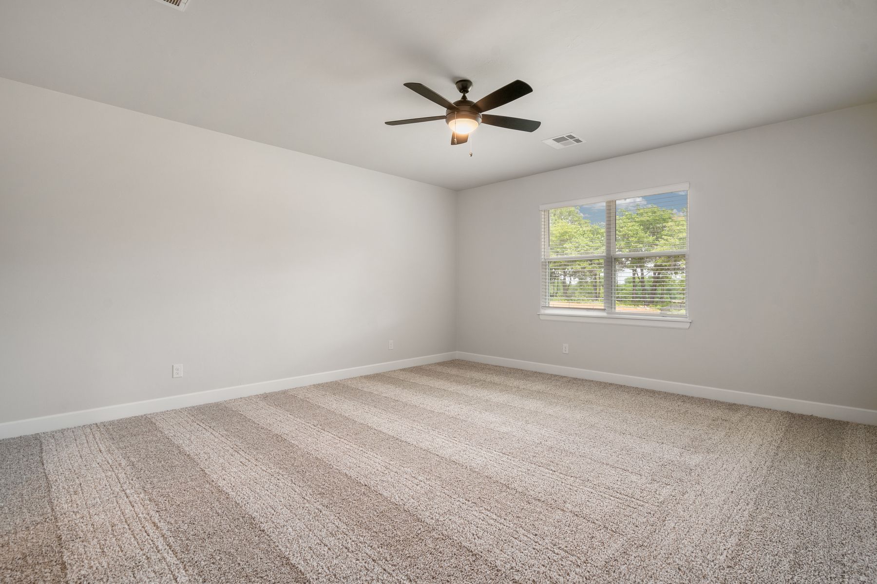 The master bedroom is spacious and has large windows with backyard views.