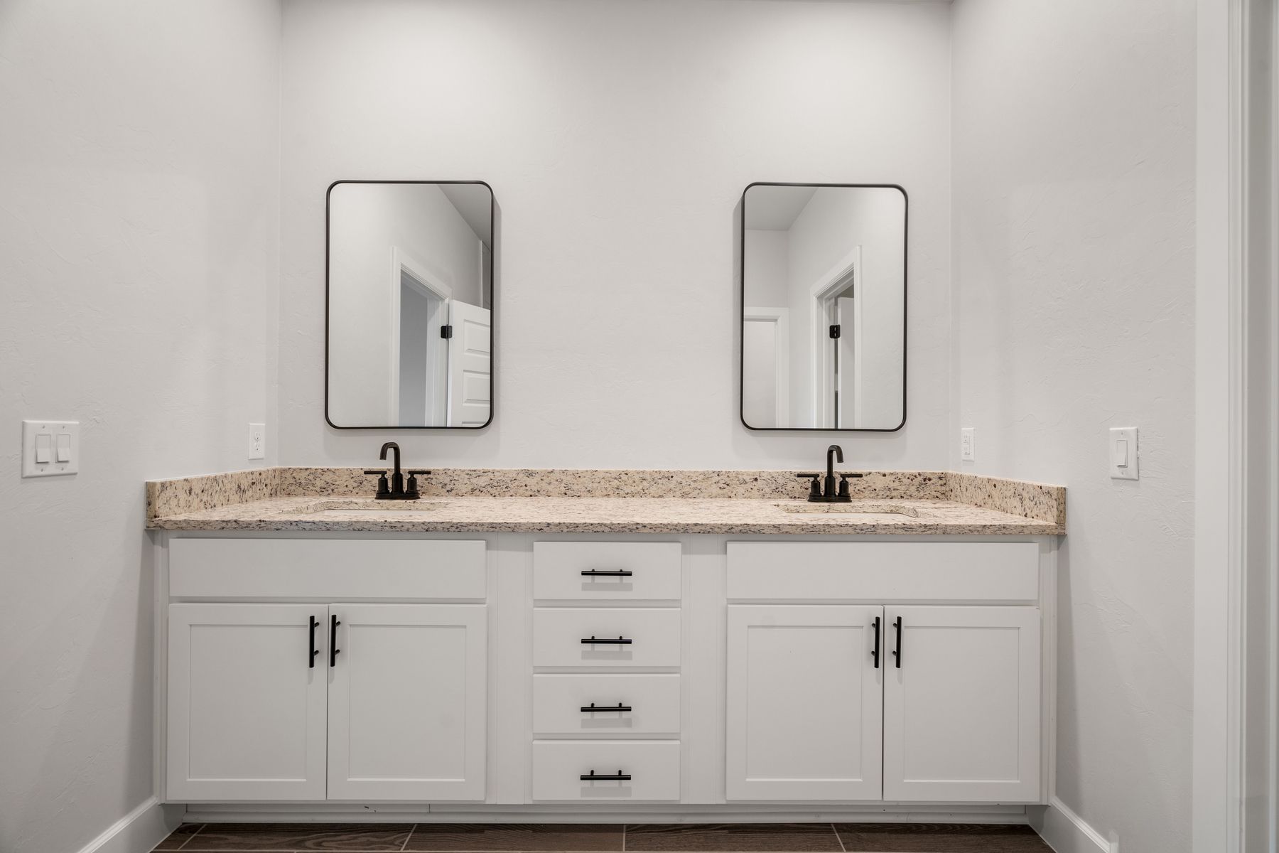 The master bathroom has a dual-sink vanity and matte black finishes.