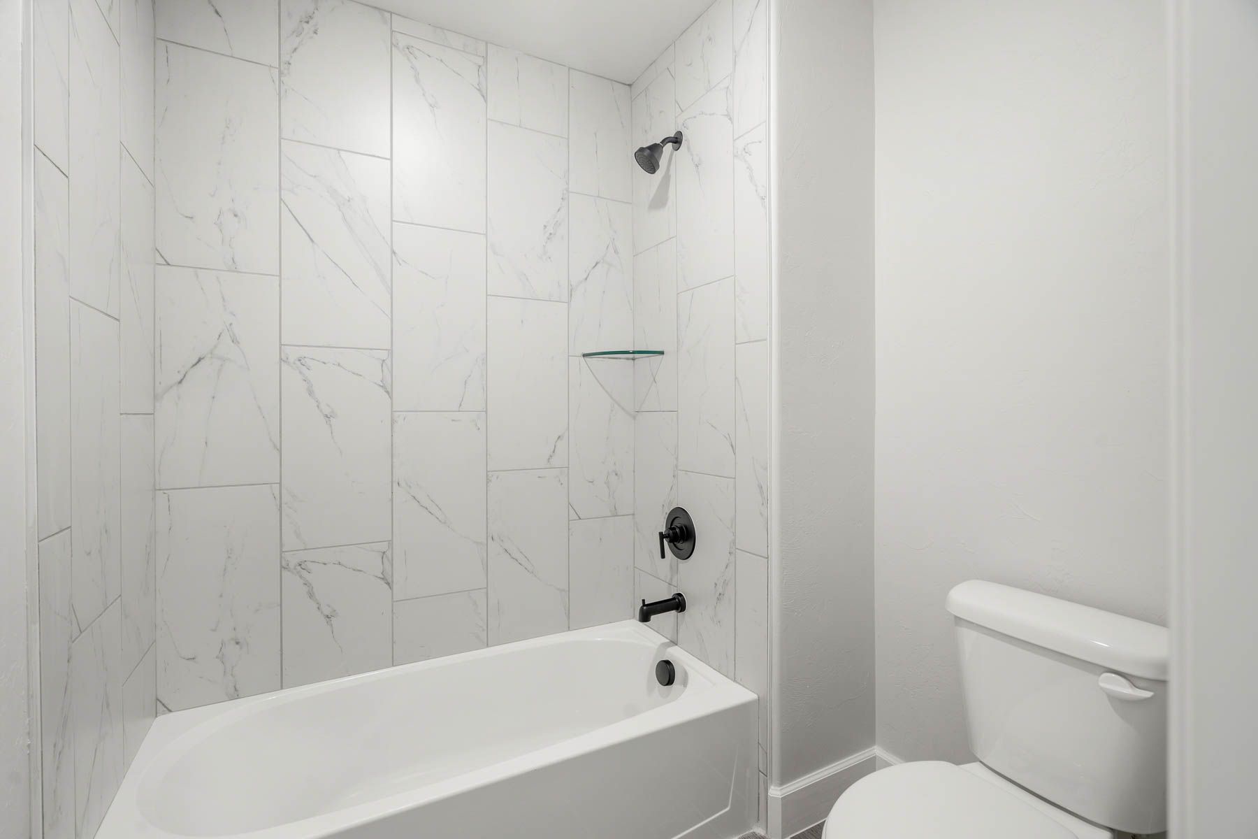 The secondary bathroom has a tiled shower-tub combo.