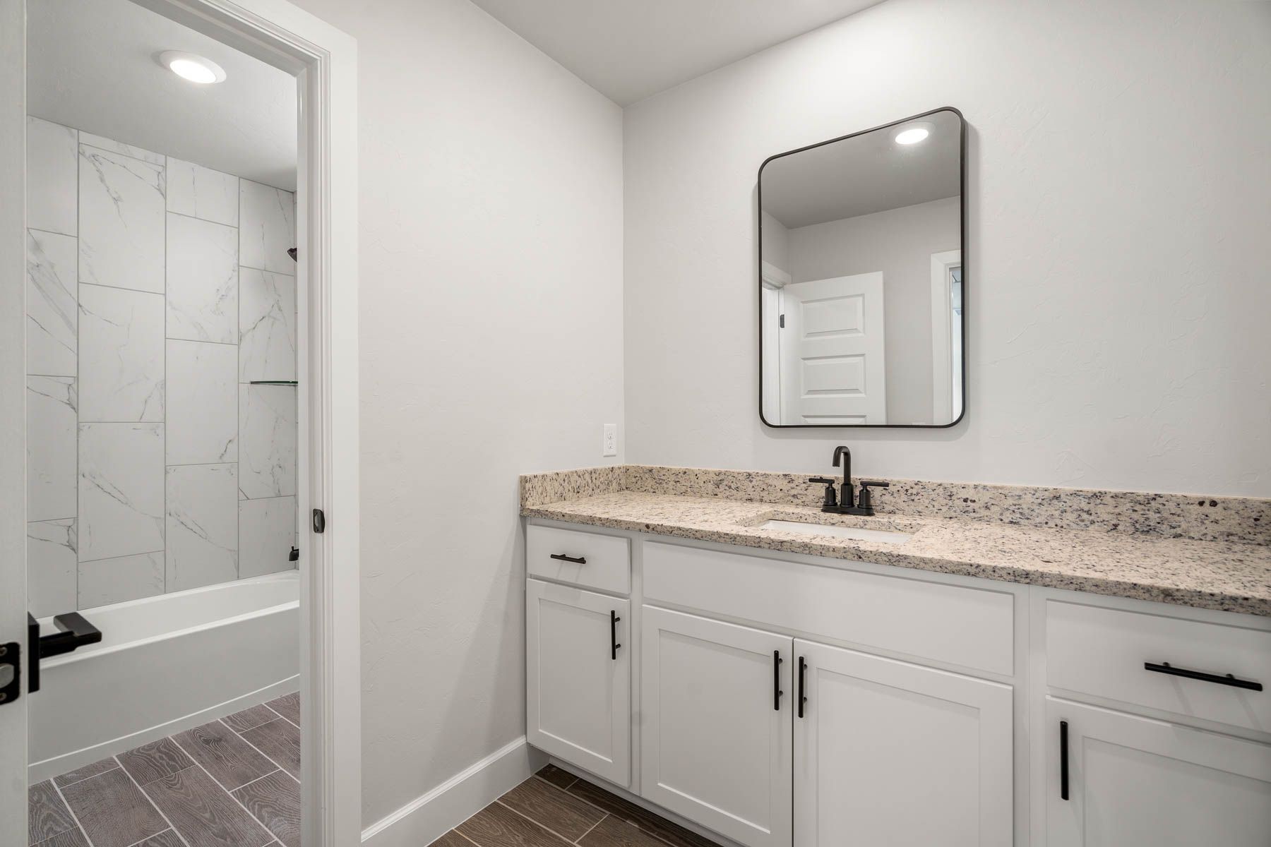 The secondary bathroom has a large vanity space with granite countertops.