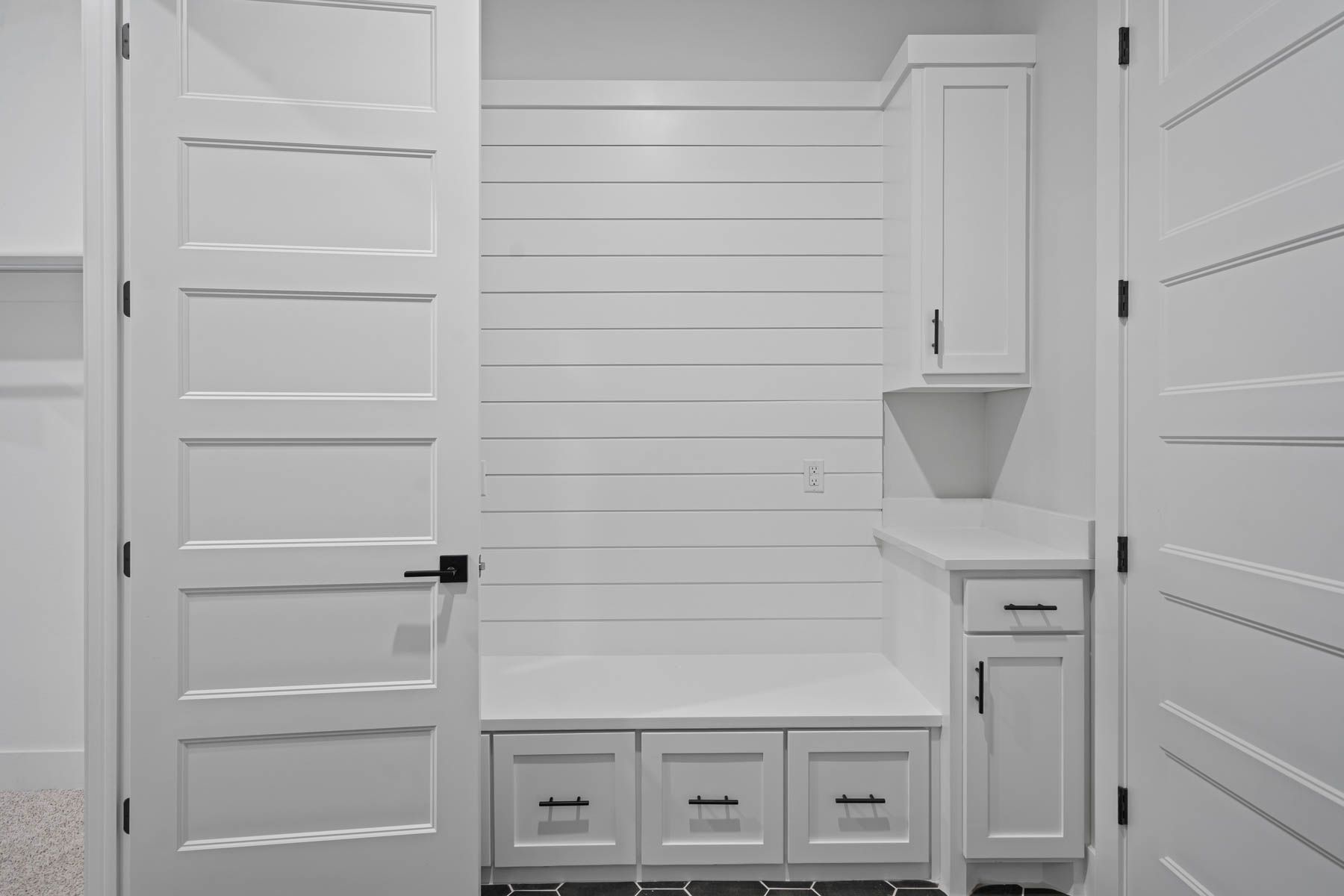 The mud room has a drop zone with drawers, cabinets and a large bench.