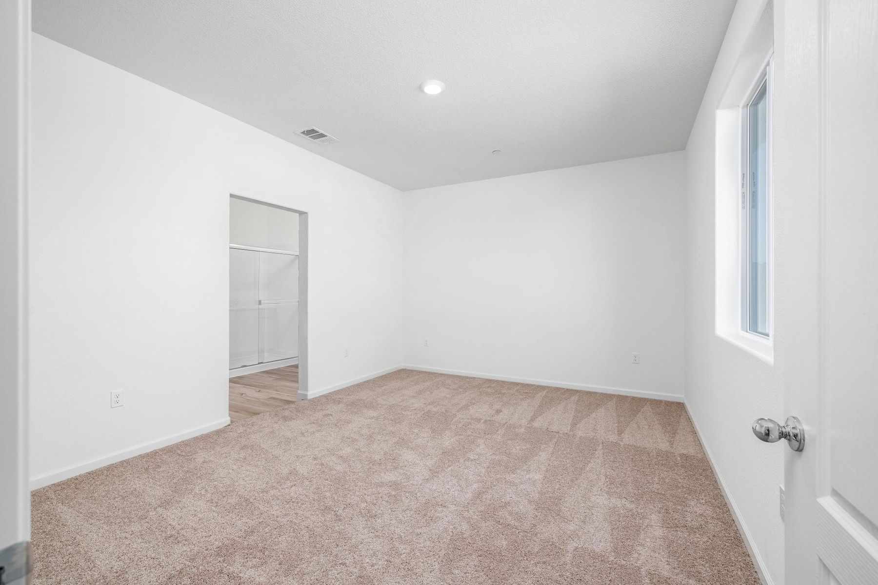 The master bedroom is spacious and has carpet.