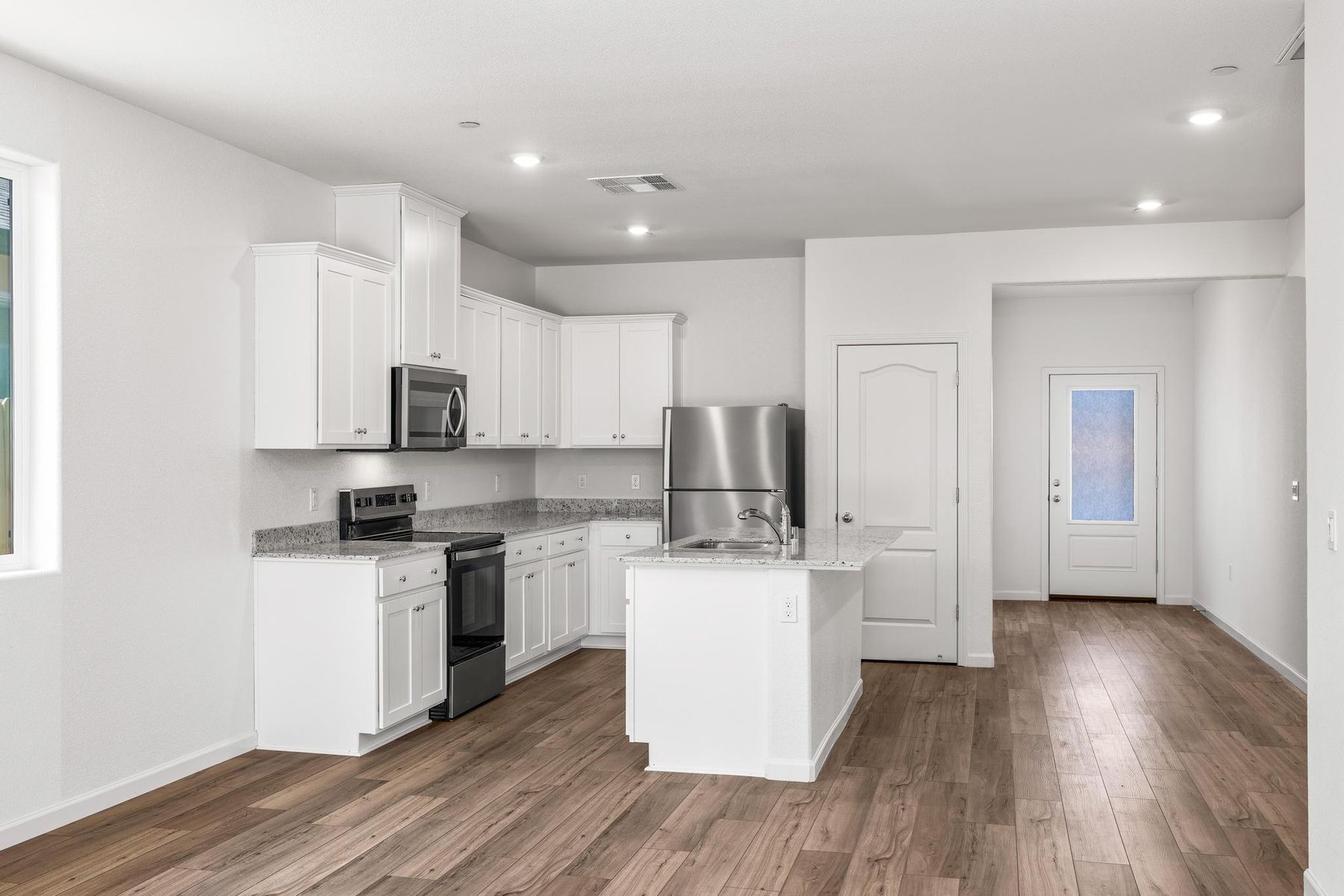 The kitchen has stainless steel appliances and plank flooring.