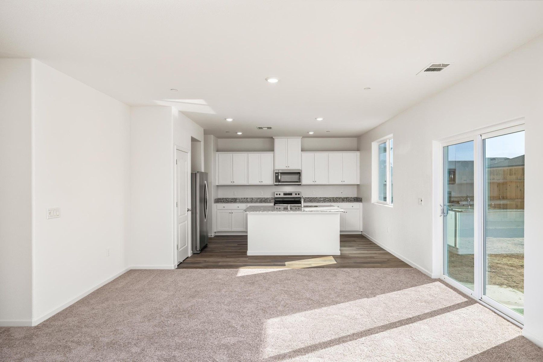 The kitchen has stainless steel appliances and plank flooring.