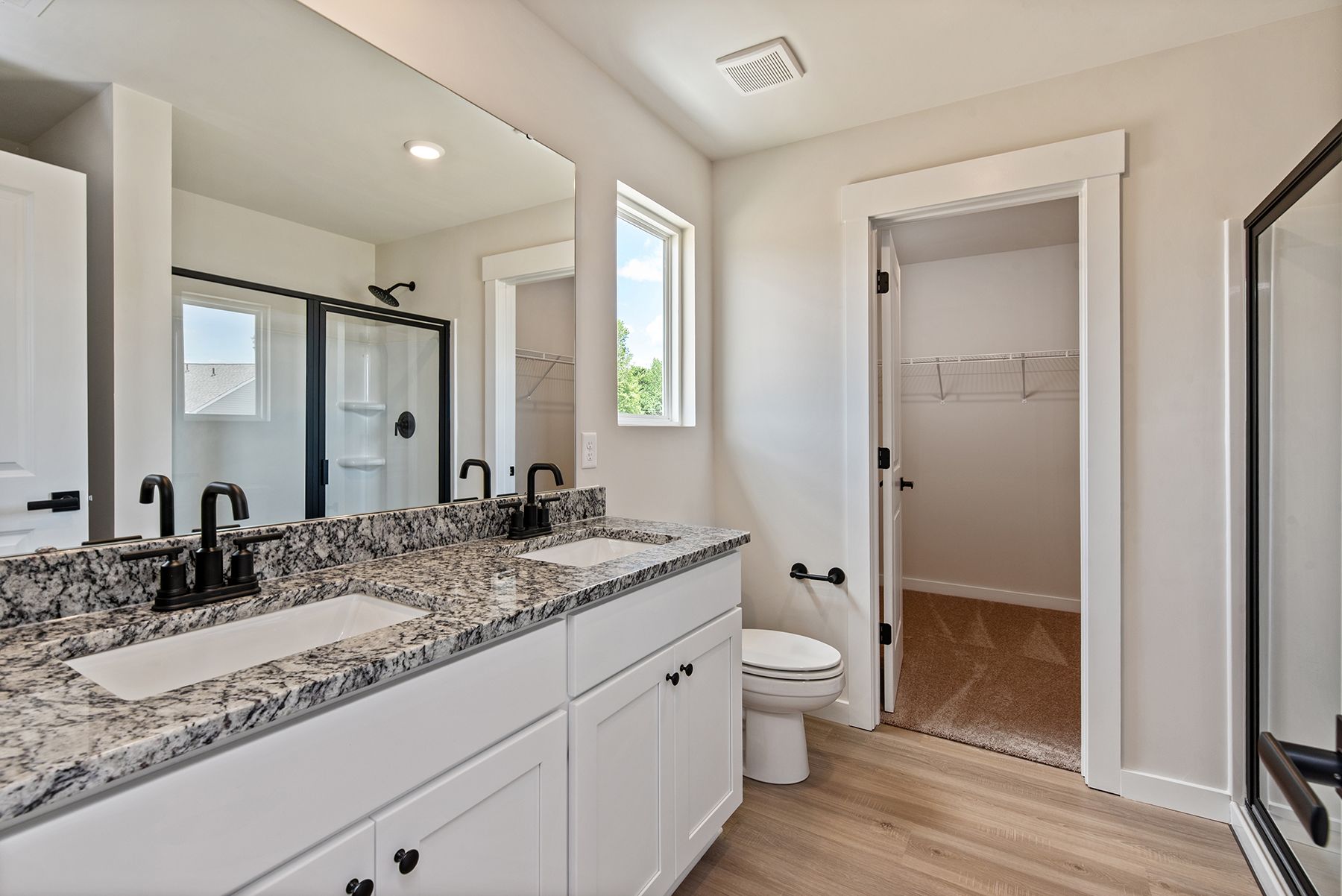 The master bedroom has large windows and carpet.