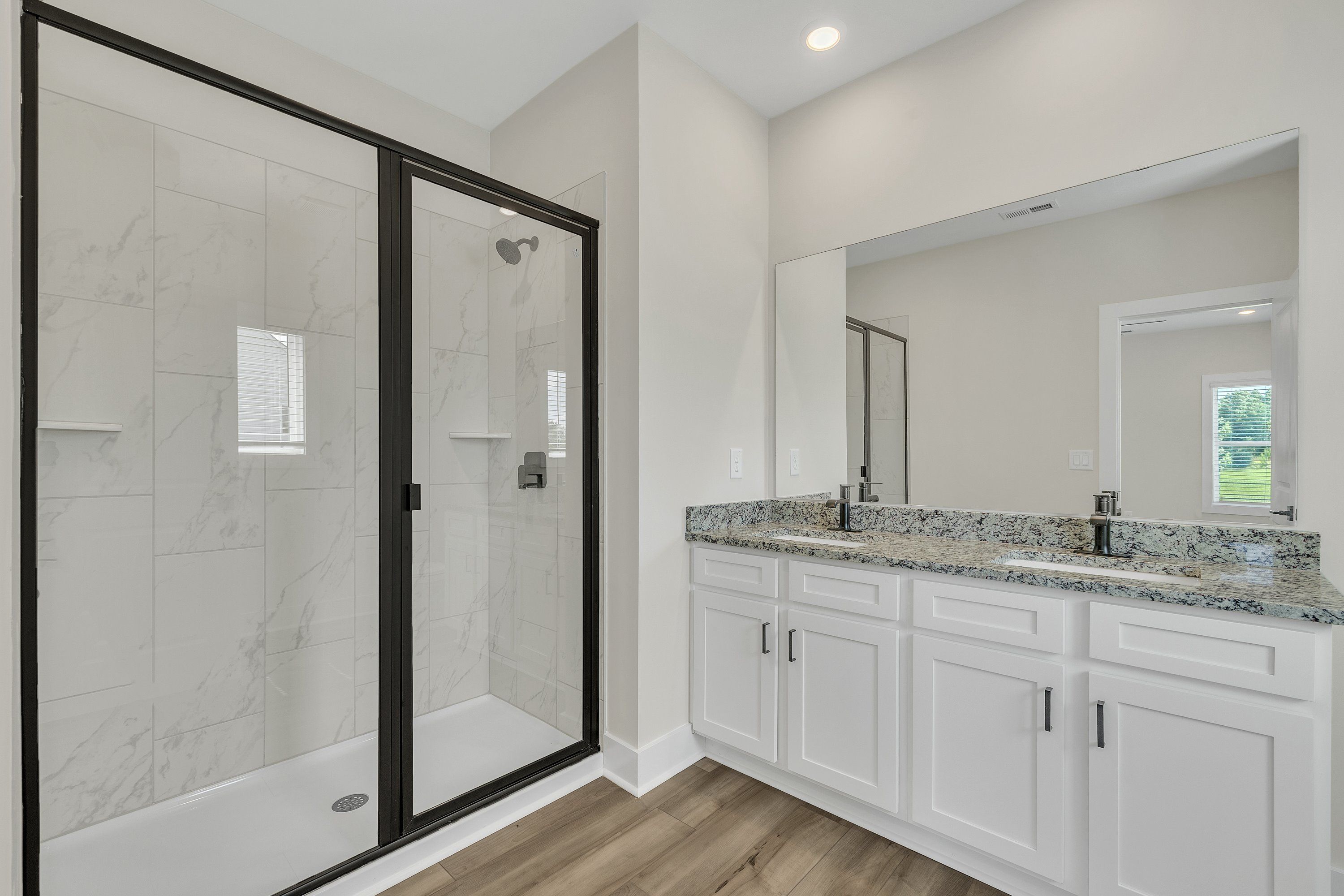 The master bathroom has double sinks and glass-enclosed shower. 