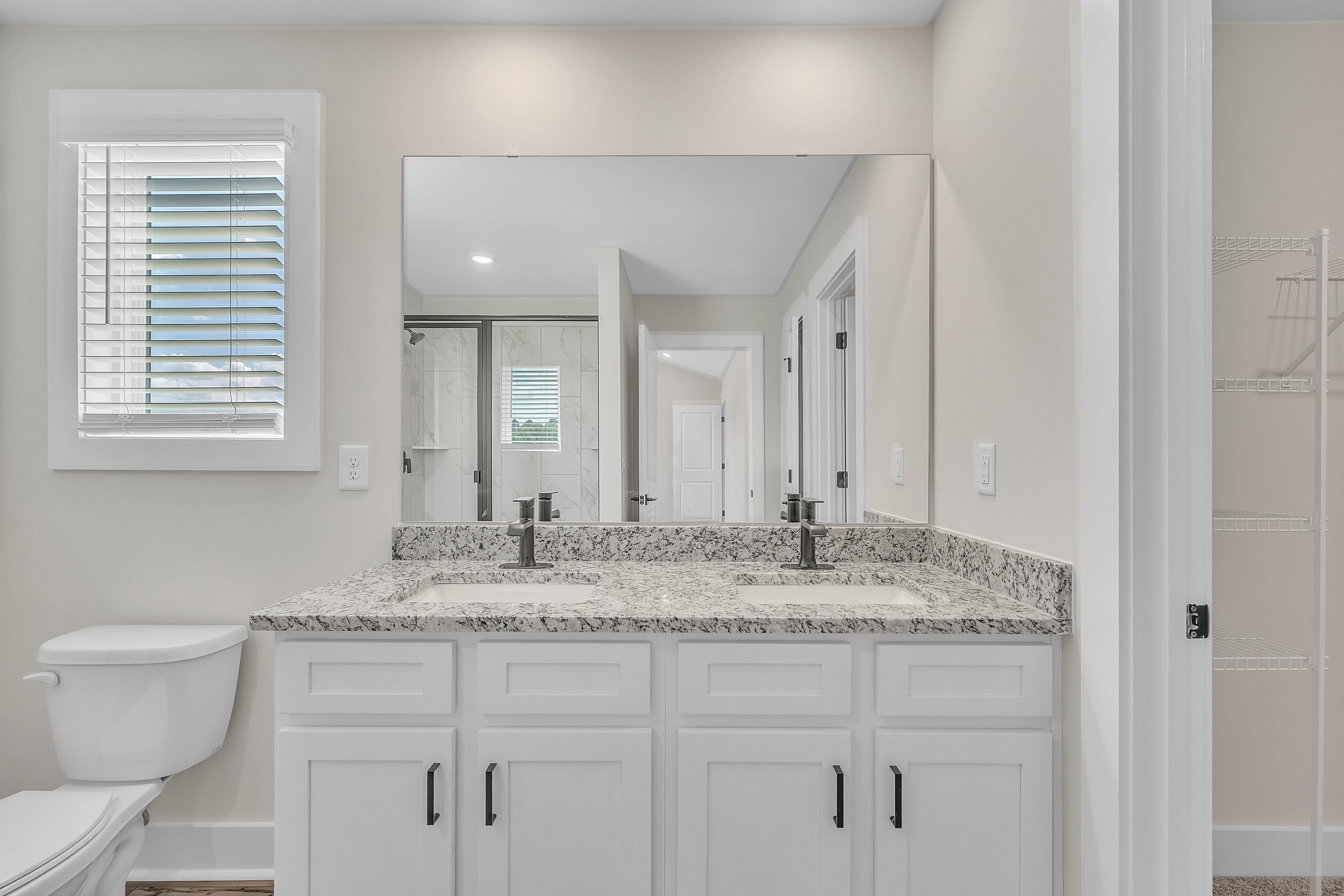 The master bathroom has dual sinks and a glass-enclosed shower.