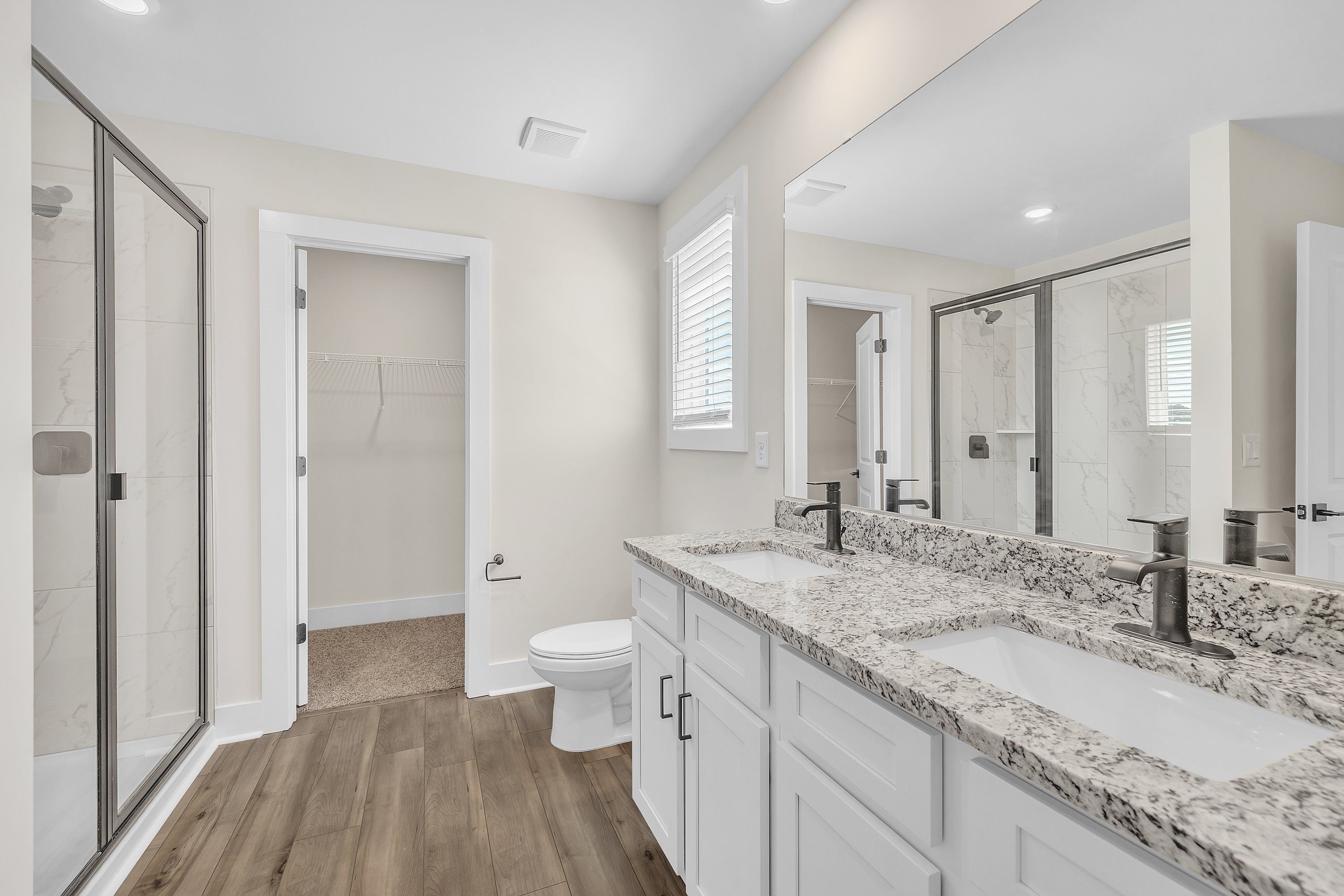 The master bathroom has dual sinks and a glass-enclosed shower.