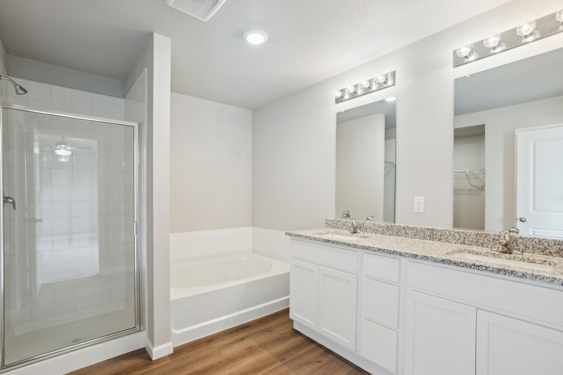 The master bathroom has a dual sink vanity with a step in shower and a soaking tub..