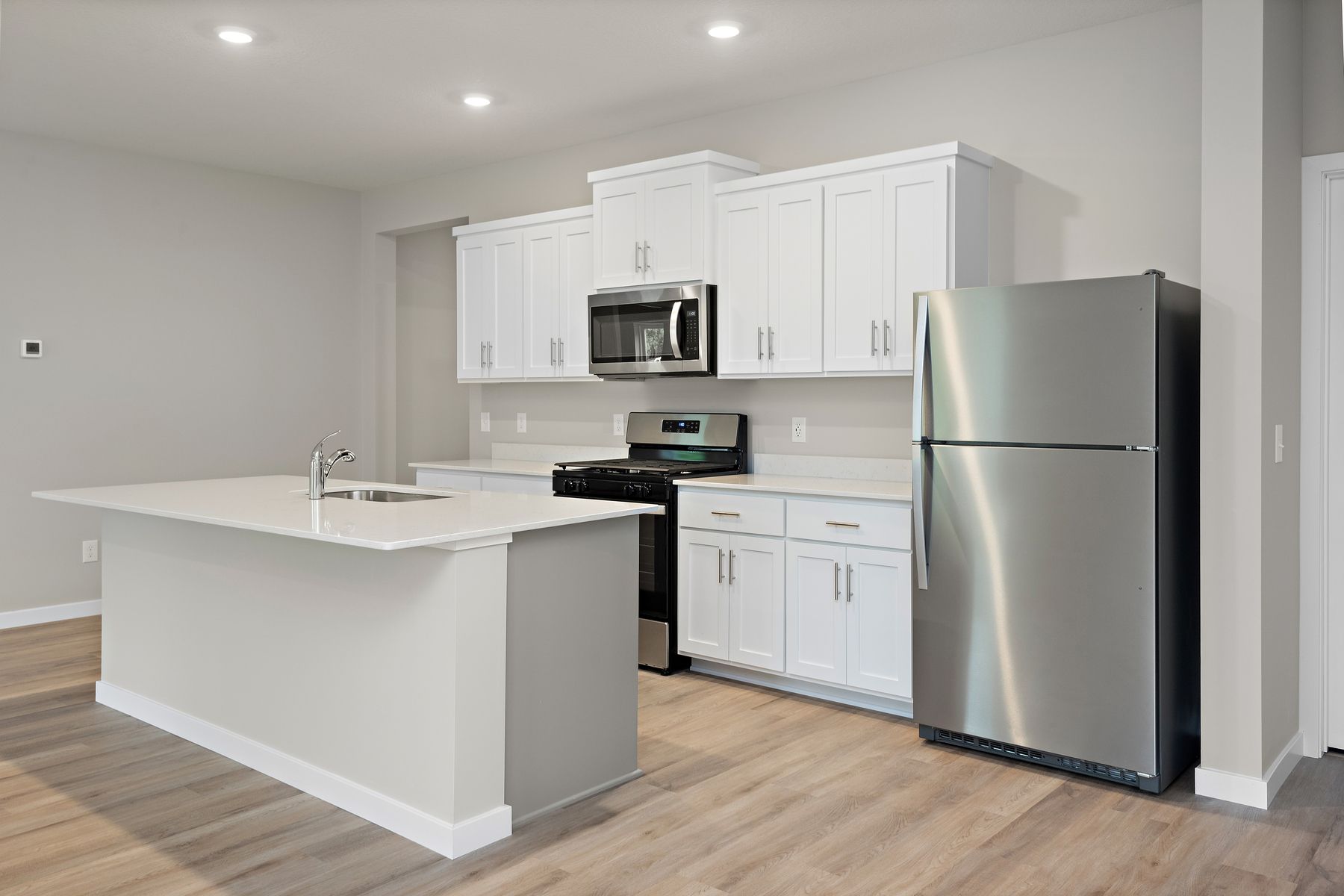 The kitchen has stainless steel appliances and plank flooring.