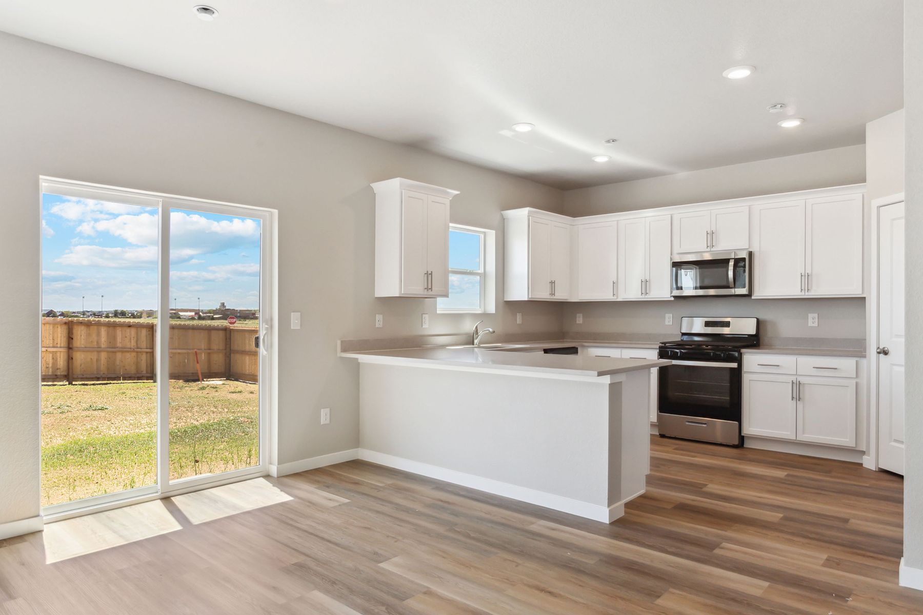 The kitchen has stainless steel appliances and plank flooring.