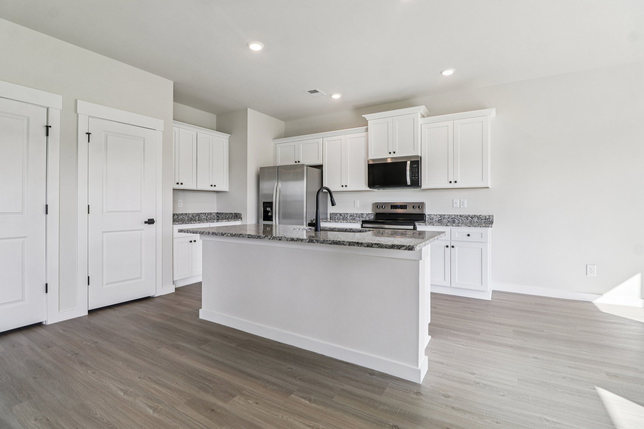 The kitchen has stainless steel appliances and plank flooring.