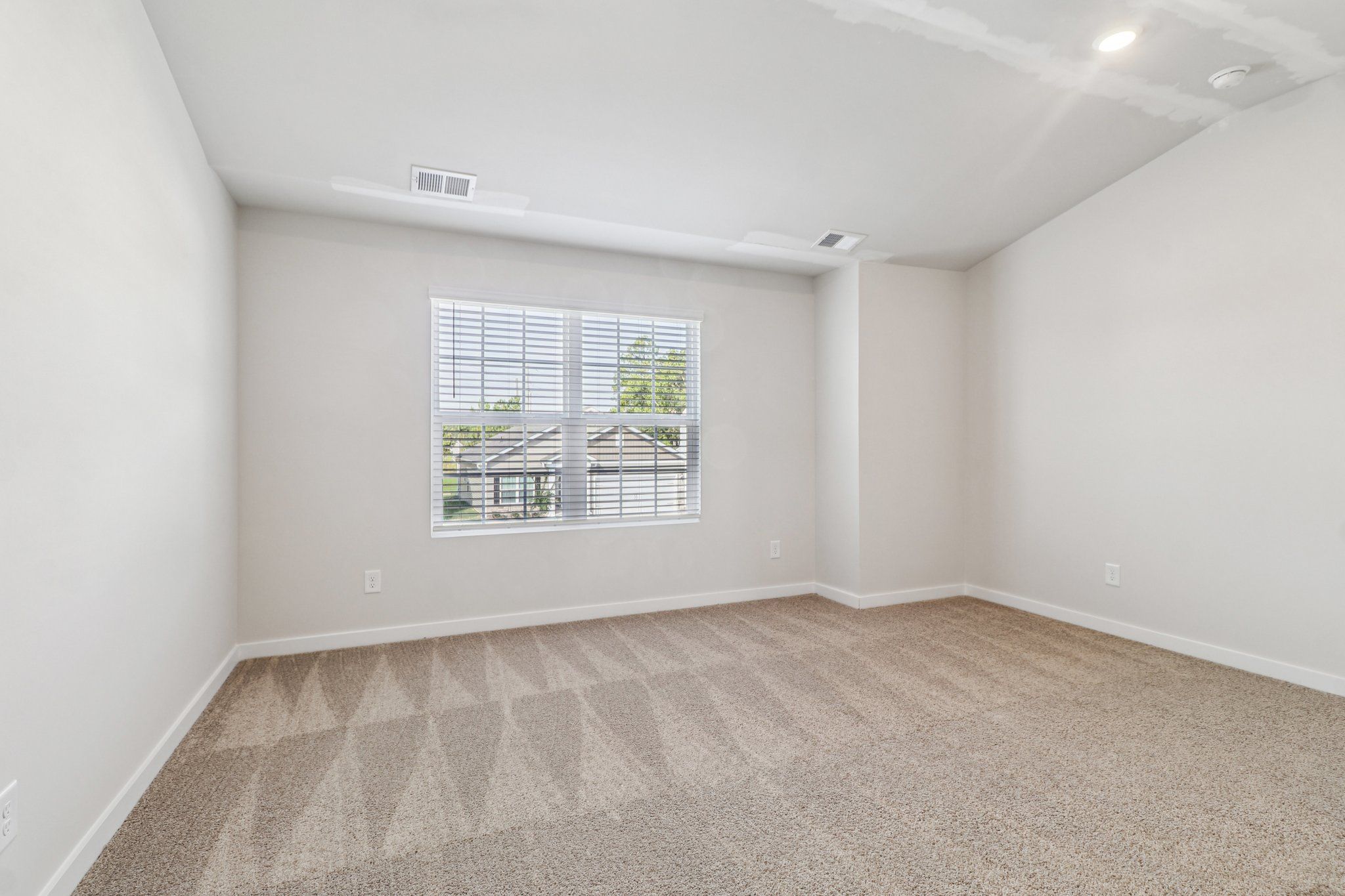 The master bedroom has large windows and carpet.