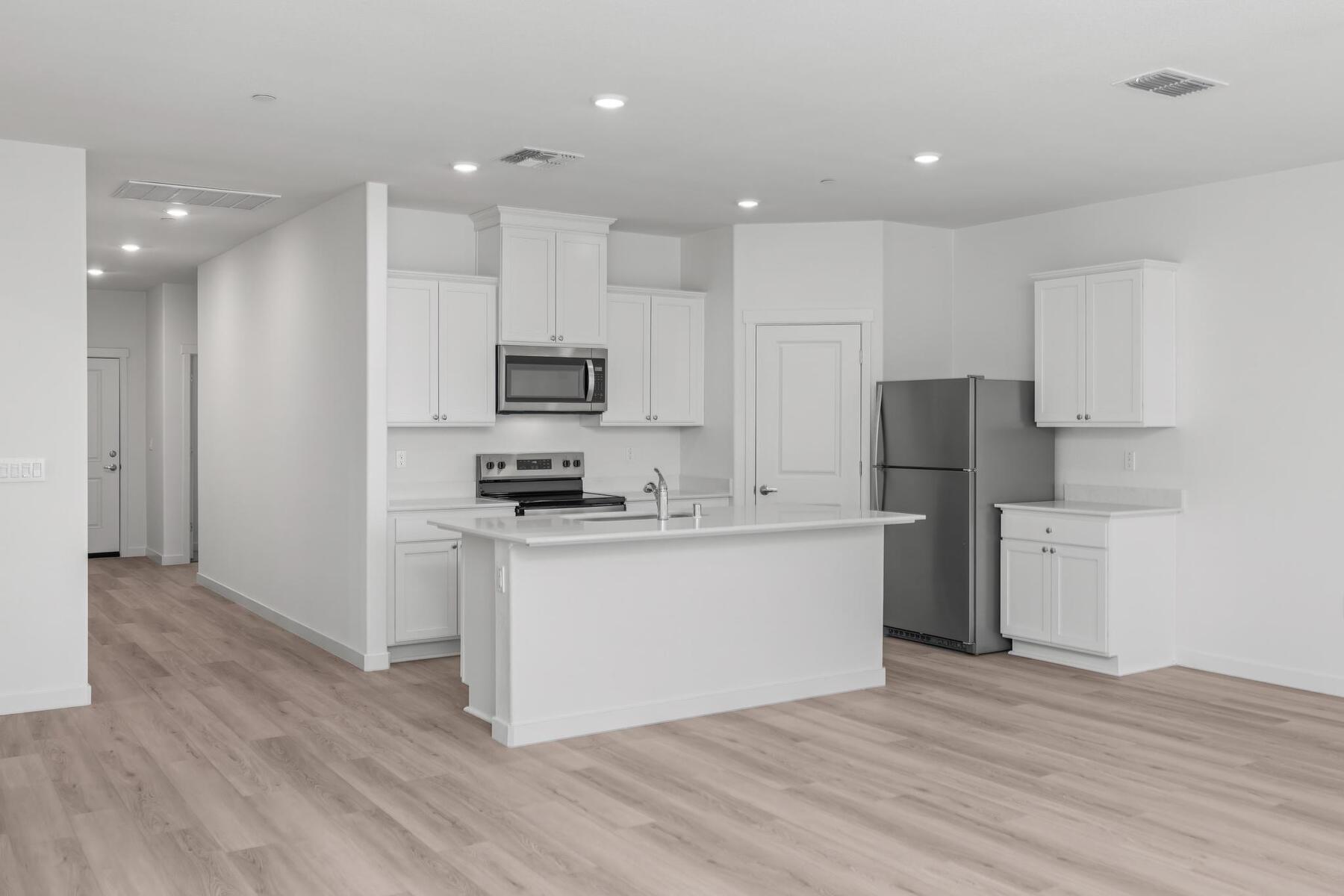 The kitchen has stainless steel appliances and plank flooring.