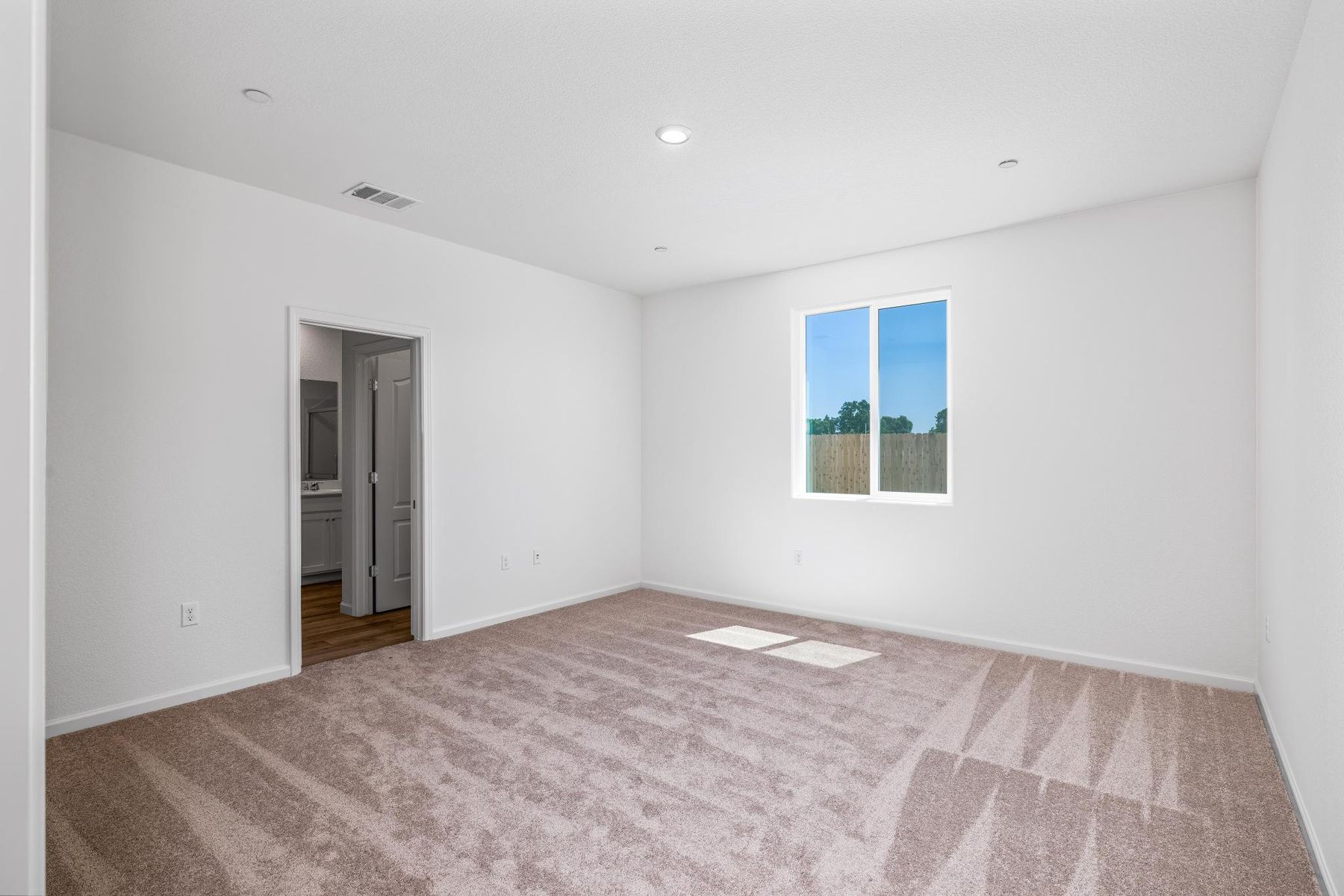 The master bedroom is spacious and has carpet.