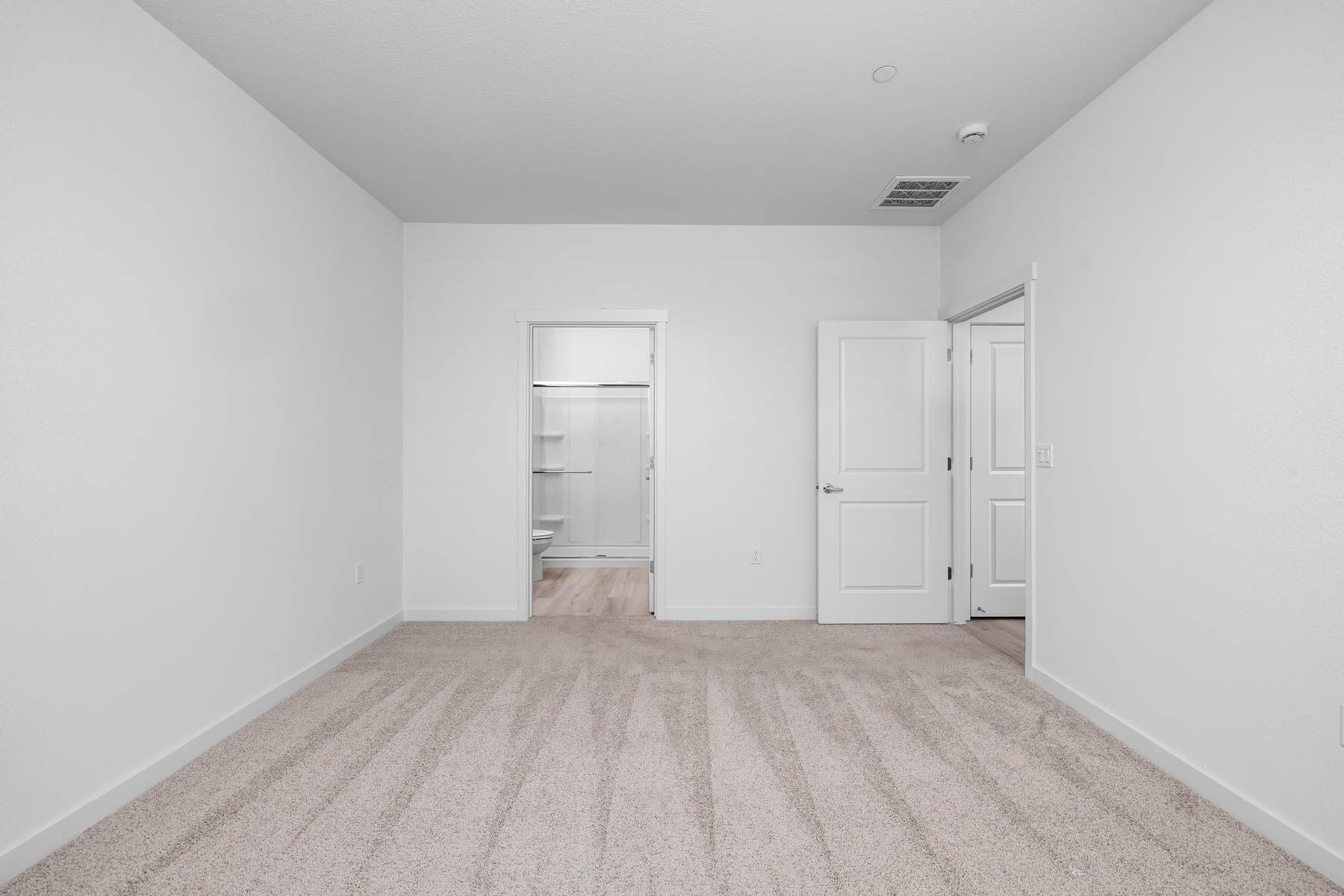 The master bedroom is spacious and has carpet.