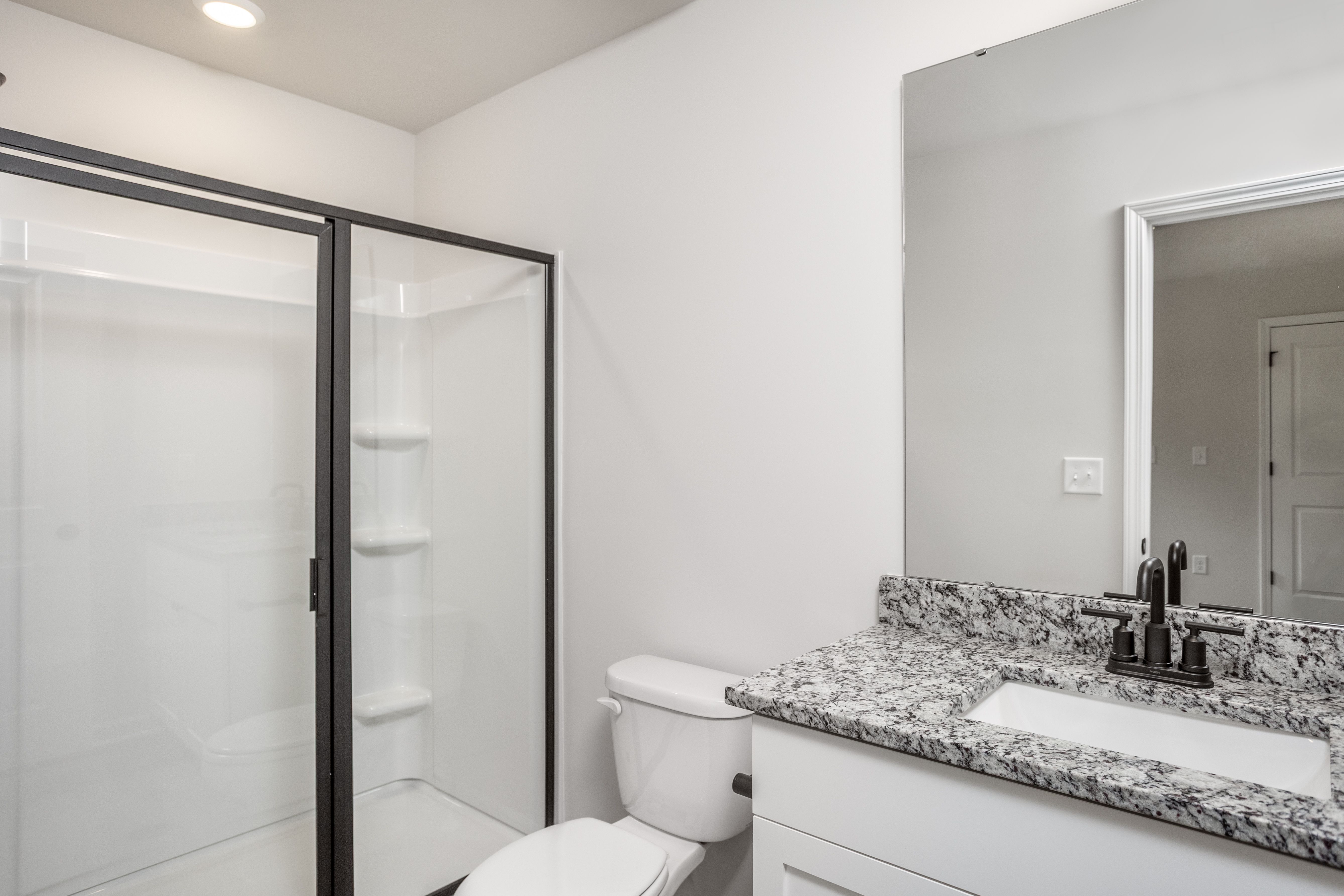 The master bathroom has a glass-enclosed shower. 