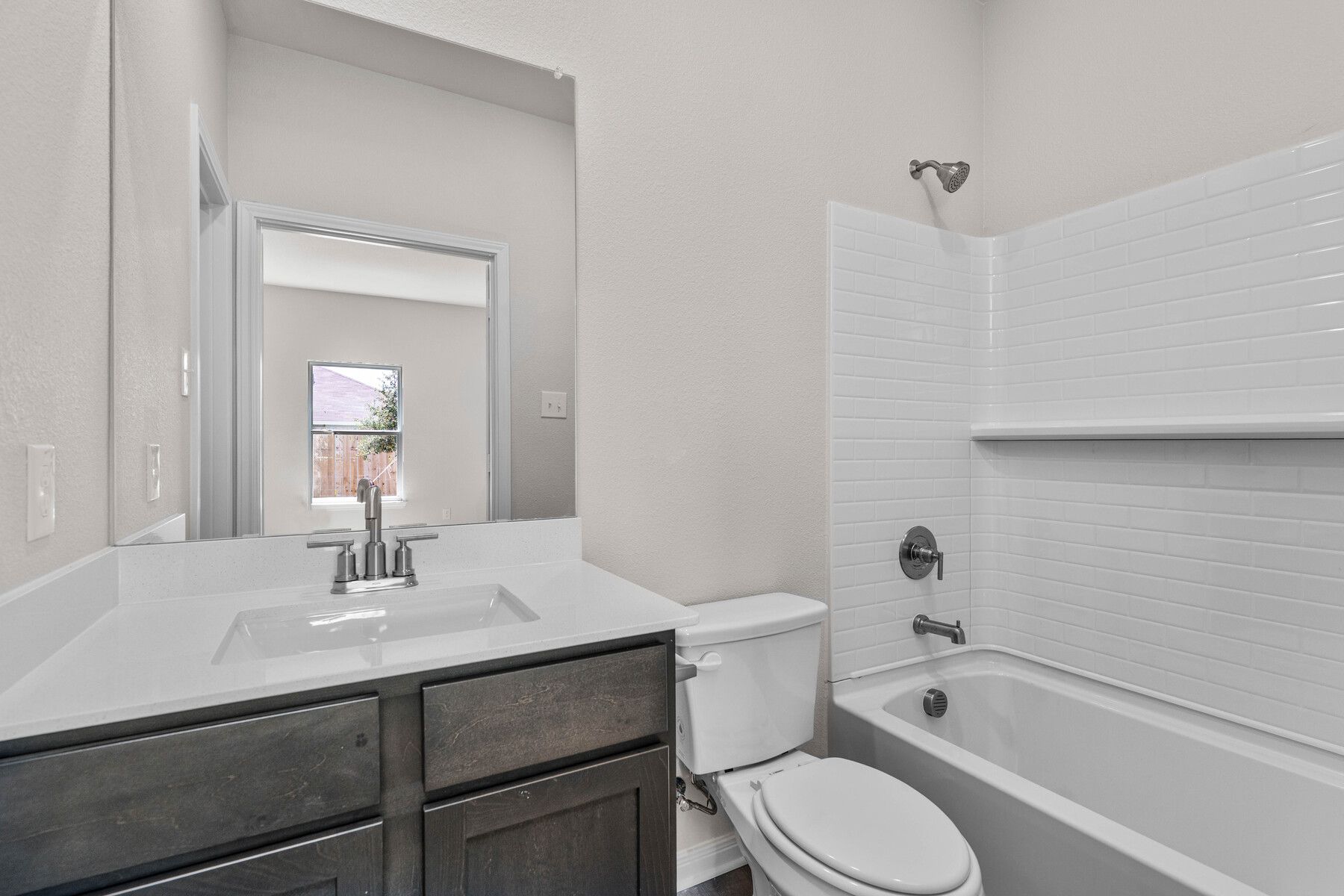 The master bathroom has a vanity and shower-tub combo.