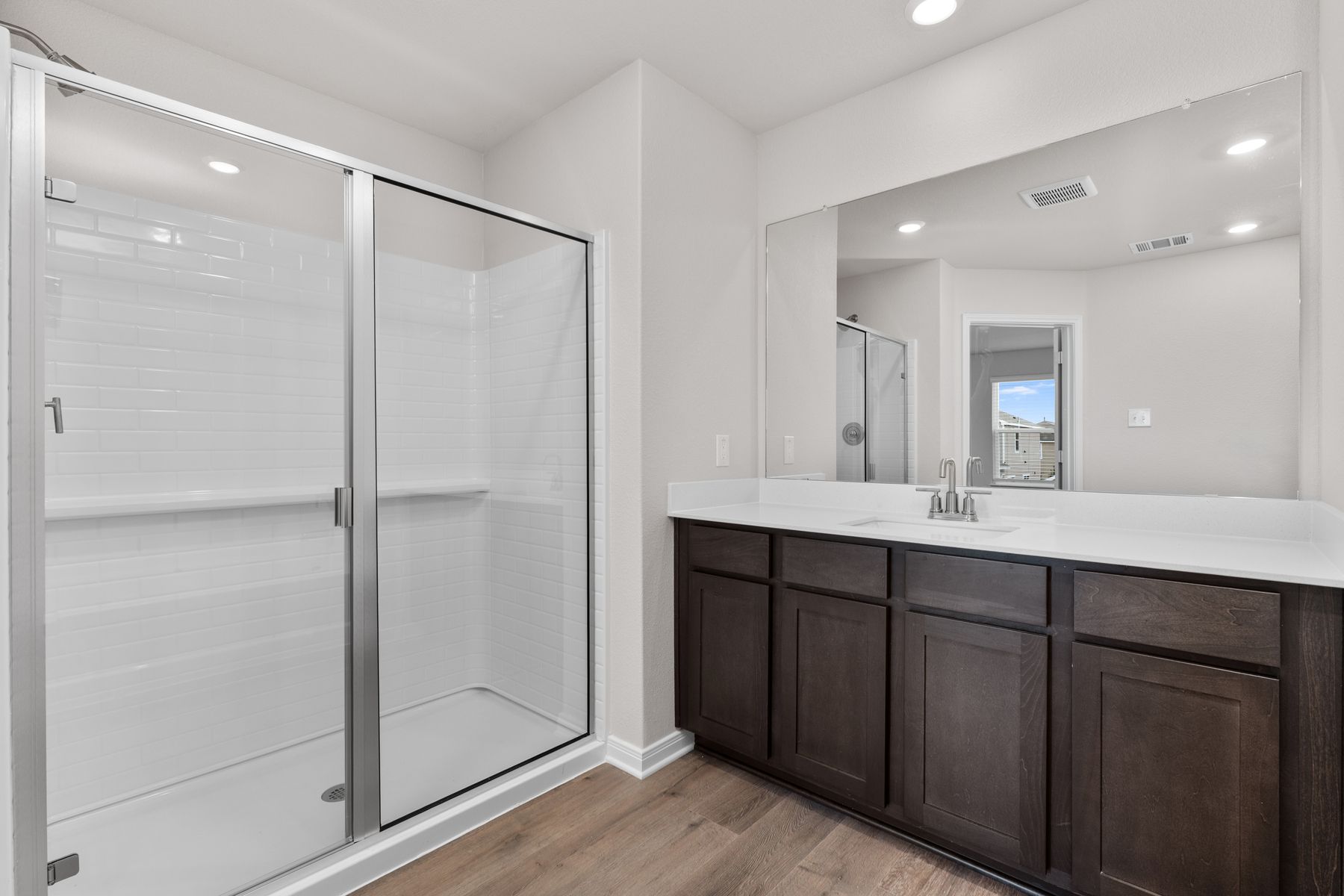 The master bathroom has a sprawling vanity and glass, walk-in shower.