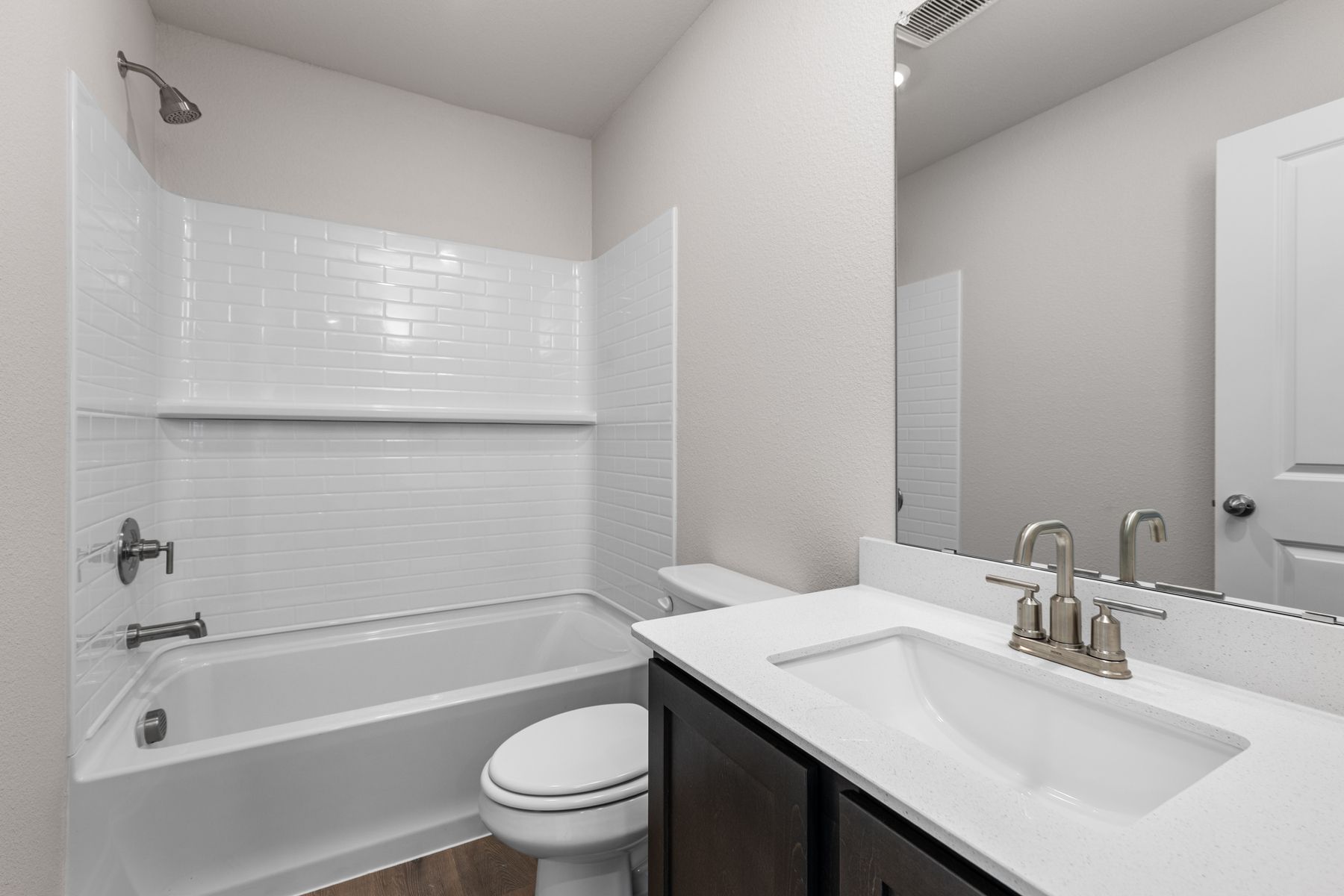 The secondary bathroom has a sprawling vanity and a shower-tub combo.