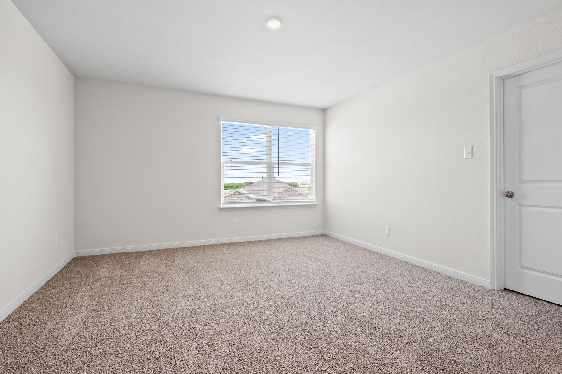 The spacious master bedroom has a large window that lets in natural light and backyard views.