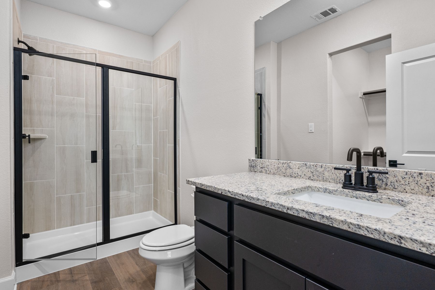 The master bathroom has a sprawling vanity and walk-in, glass shower.