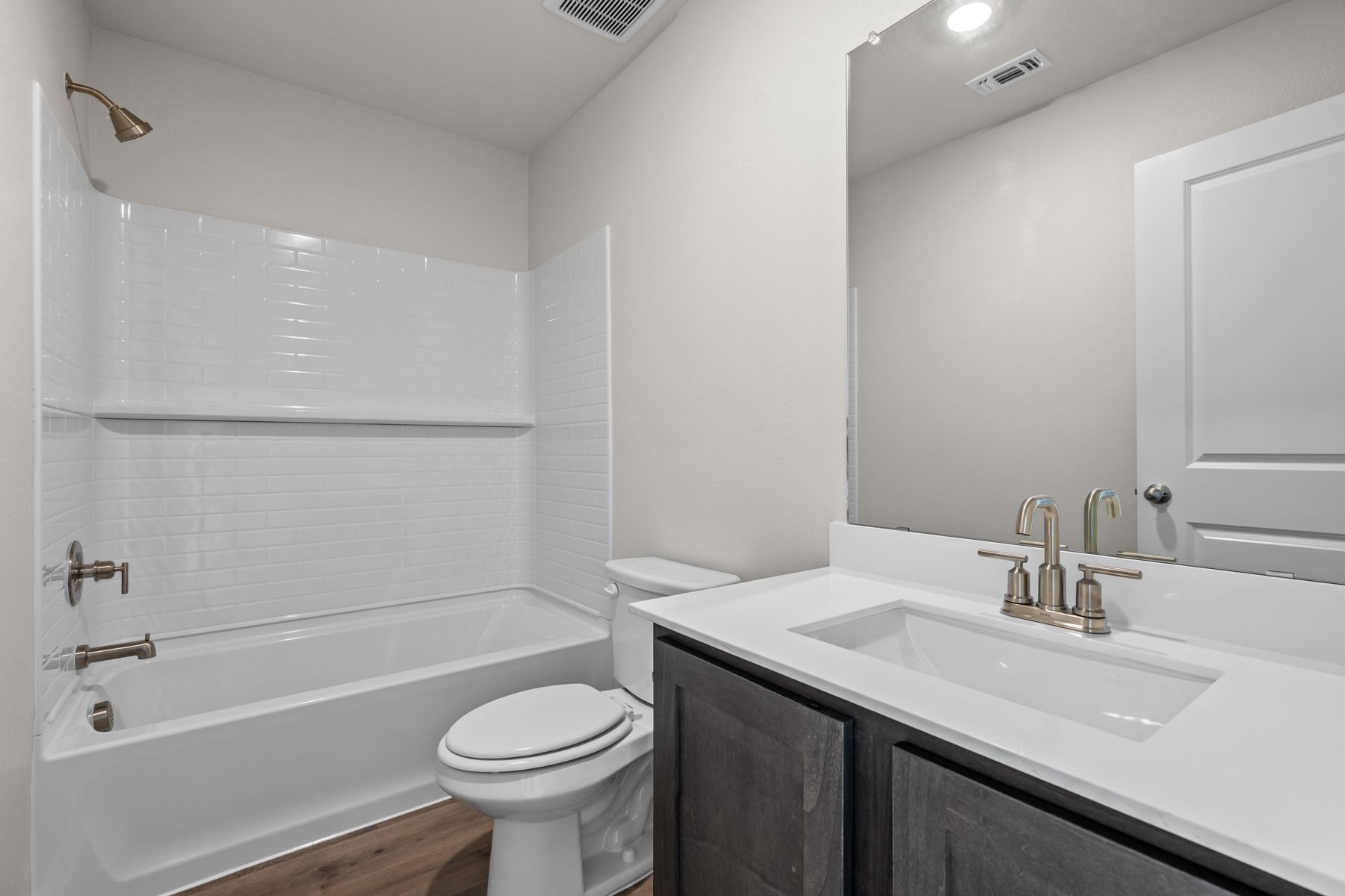 The secondary bathroom has a sprawling quartz vanity and shower-tub combo.
